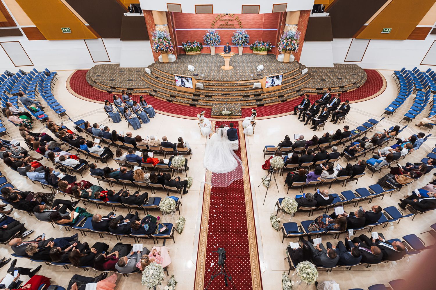 Vista aérea de ceremonia en amplia iglesia; novios en pasillo central, invitados sentados. Boda IDMJI