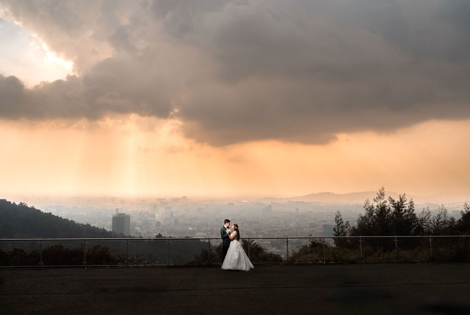Silueta de novios en colina contemplando atardecer dramático en su boda