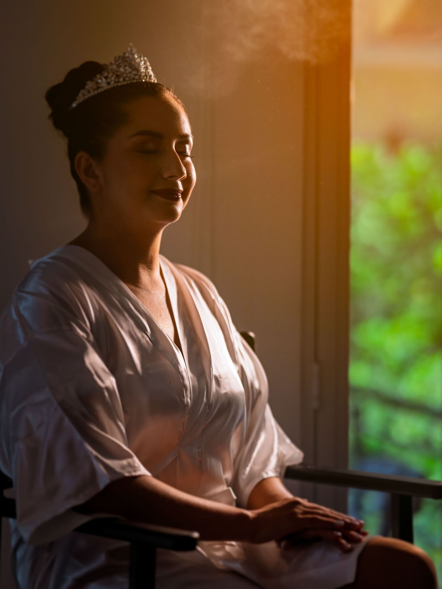 Retrato de la novia mirando por la ventana durante los preparativos de la boda
