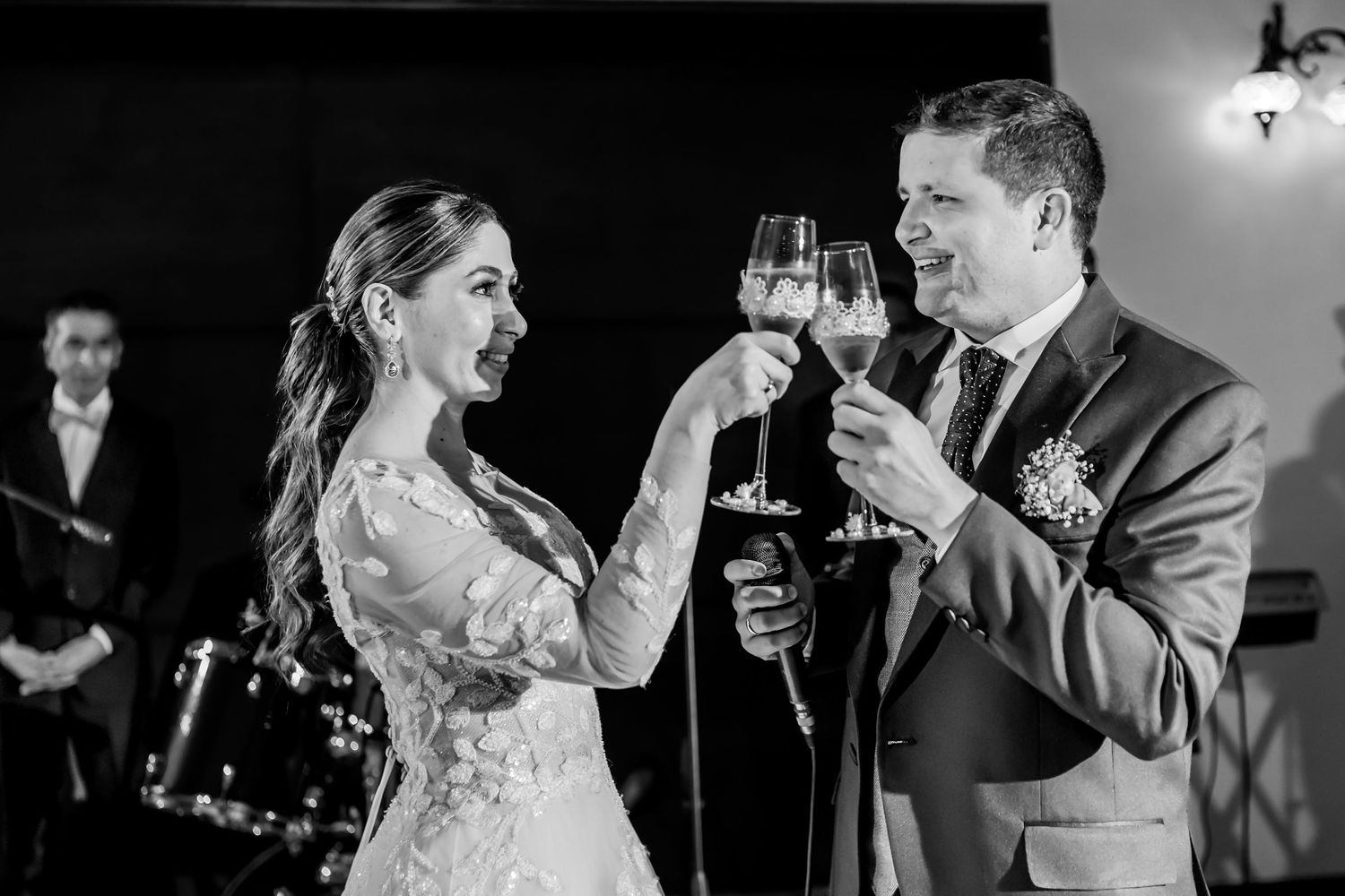 Pareja de recién casados ríe y brinda con champagne. Momento alegre en recepción de boda en blanco y negro.