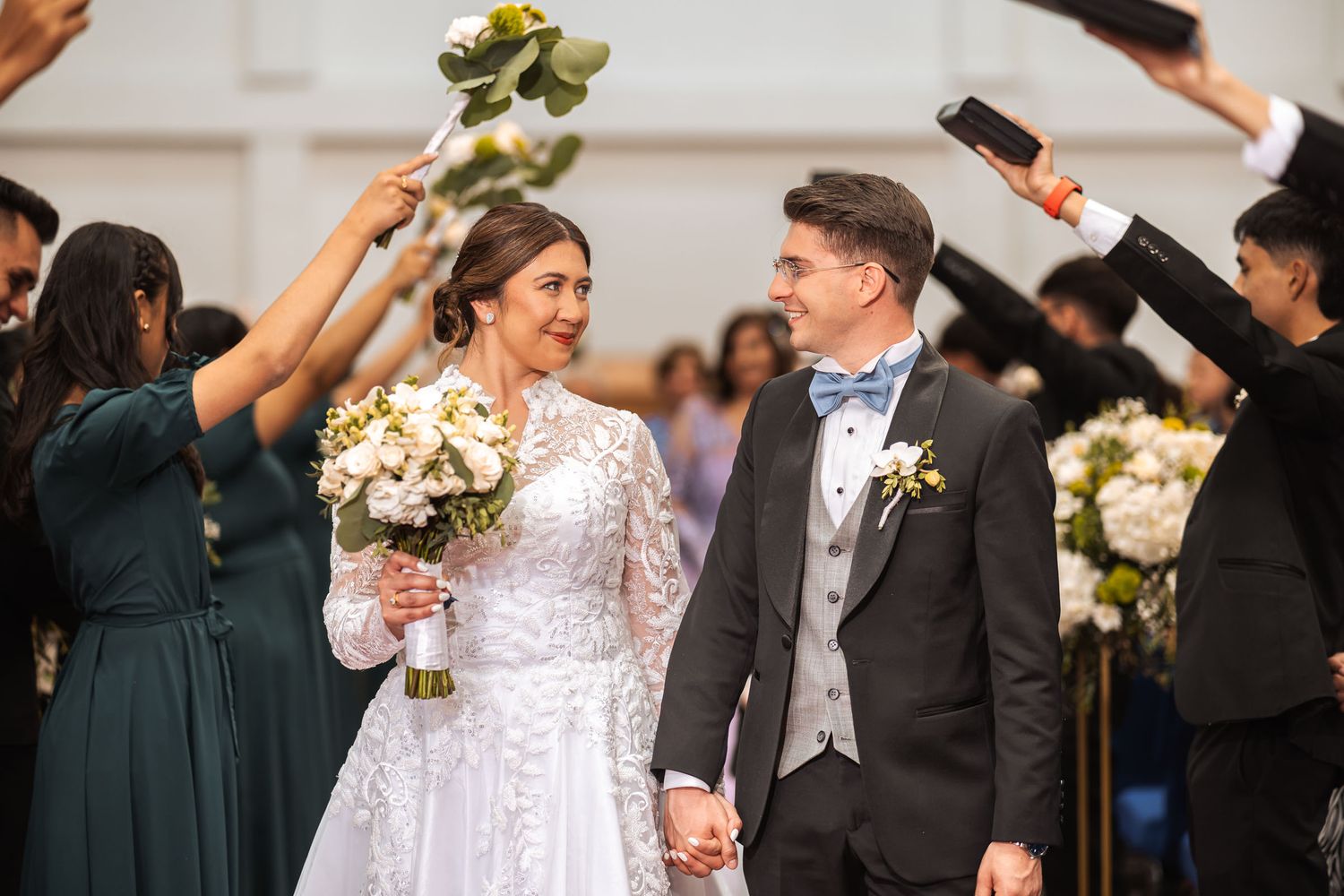 Novios recién casados caminando sonrientes por pasillo de iglesia, invitados aplauden y celebran su boda IDMJI.