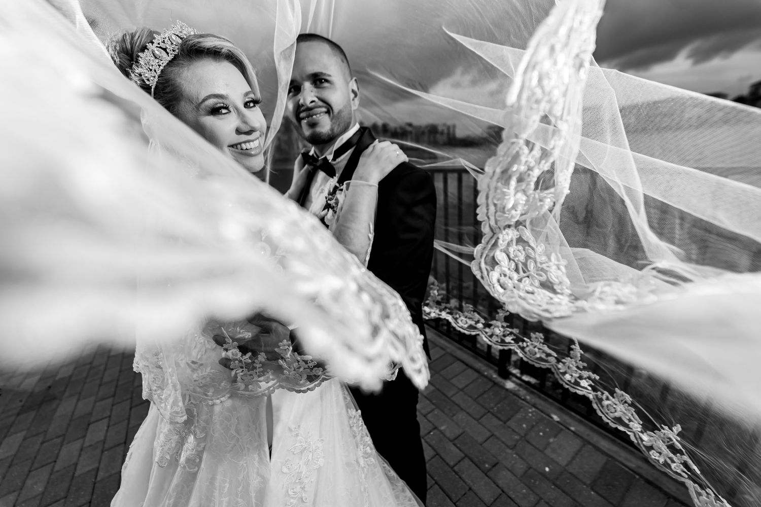 Foto B&W artística: Novios vistos a través del velo de encaje flotante de la novia en terraza. Boda en Miami.