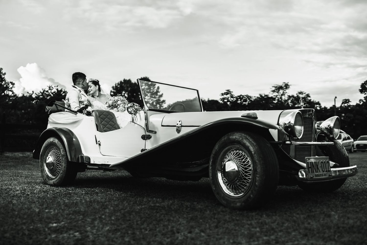 Fotografía artística en blanco y negro de los novios posando en un carro de época