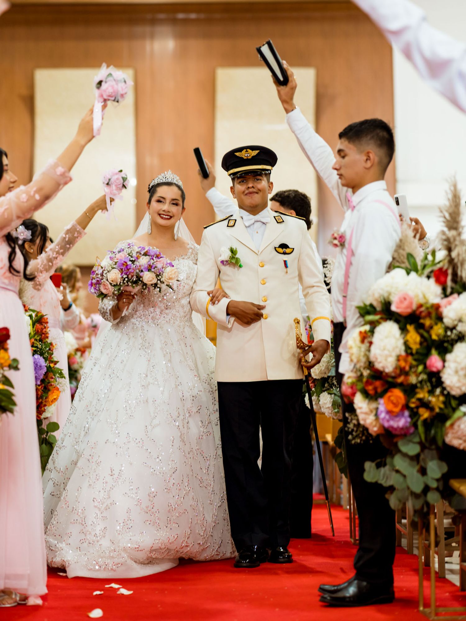 Salida de la boda, con los novios caminando por el pasillo rojo mientras los invitados celebra