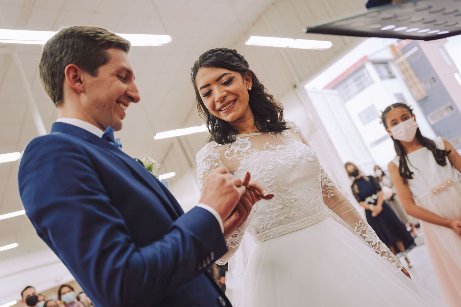Novio sonriente colocando el anillo a la novia durante la ceremonia de boda.