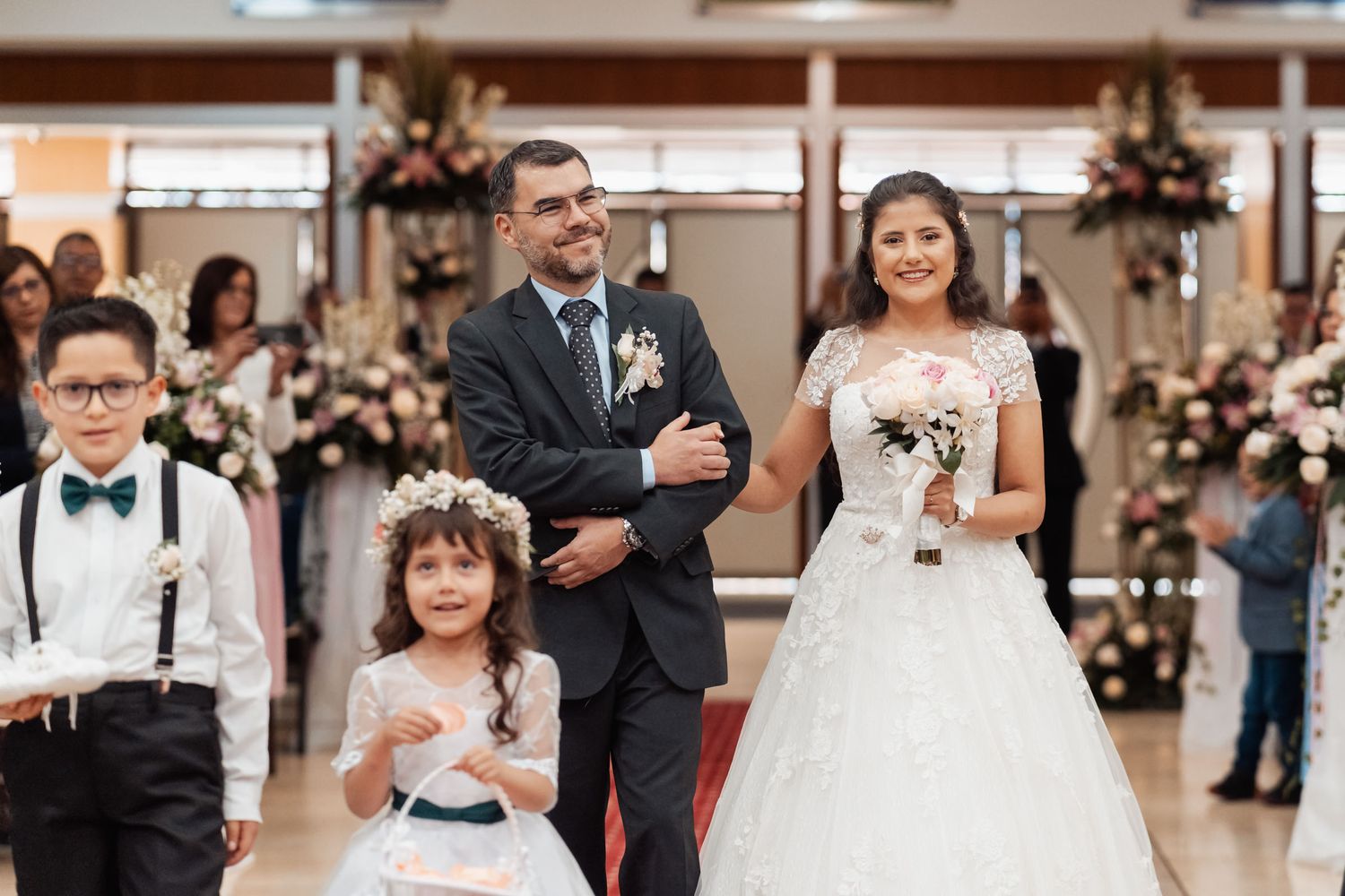 Novia escoltada por su padre caminando al altar precedida por pajecitos
