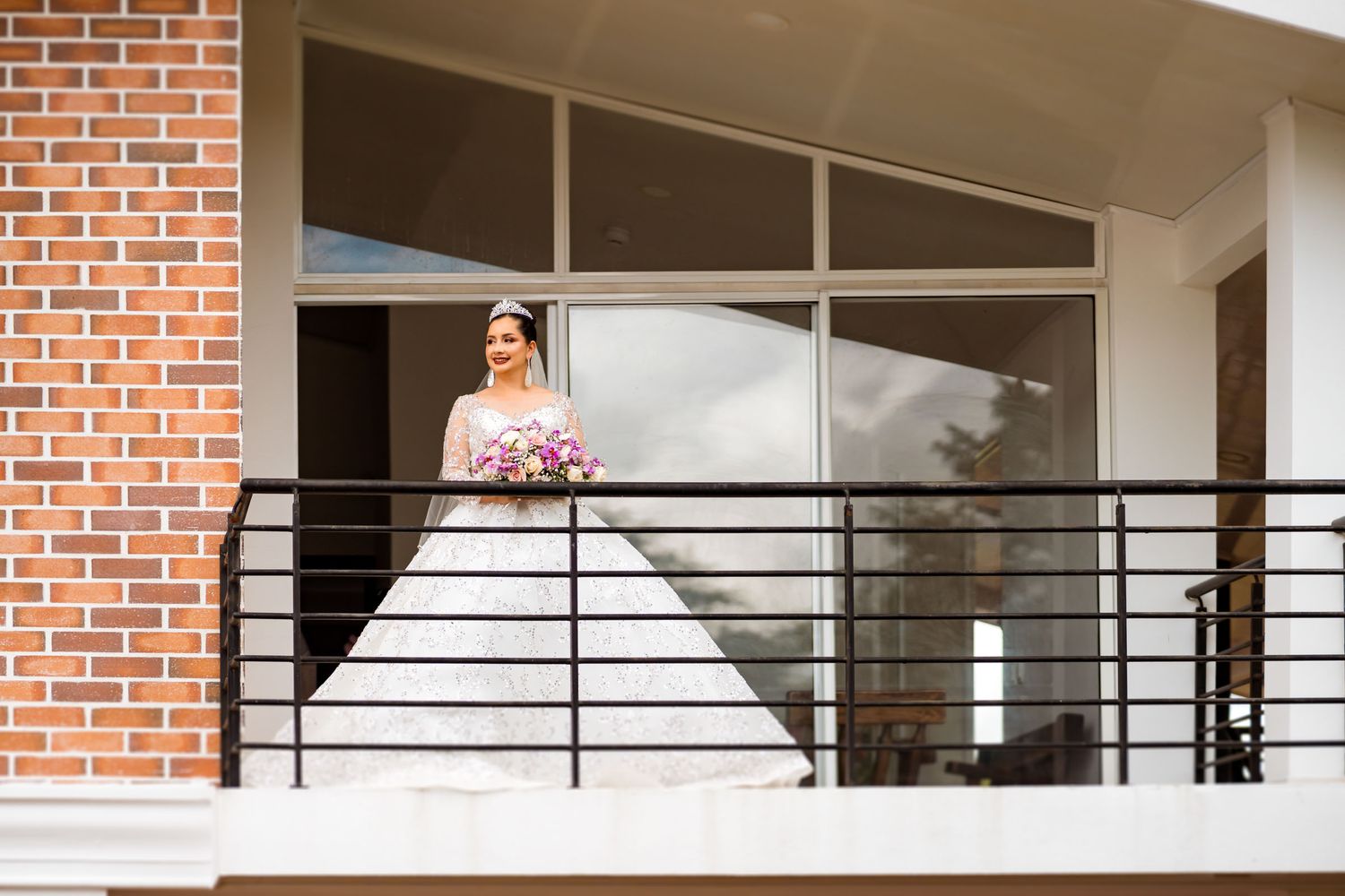 Novia espera en el balcón de una casa moderna antes de la ceremonia de su boda