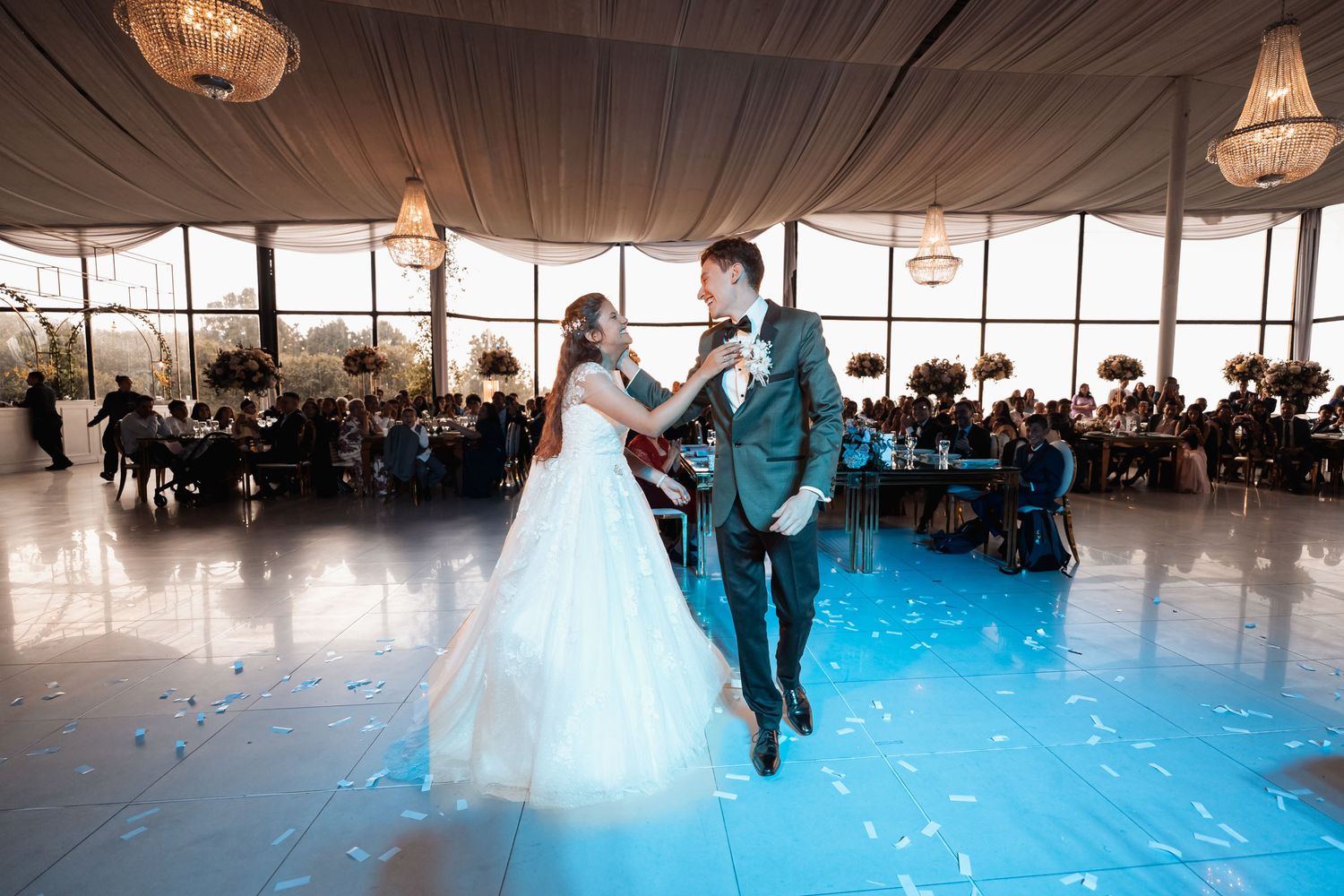 Novios bailando en pista azul iluminada durante elegante recepción de boda.