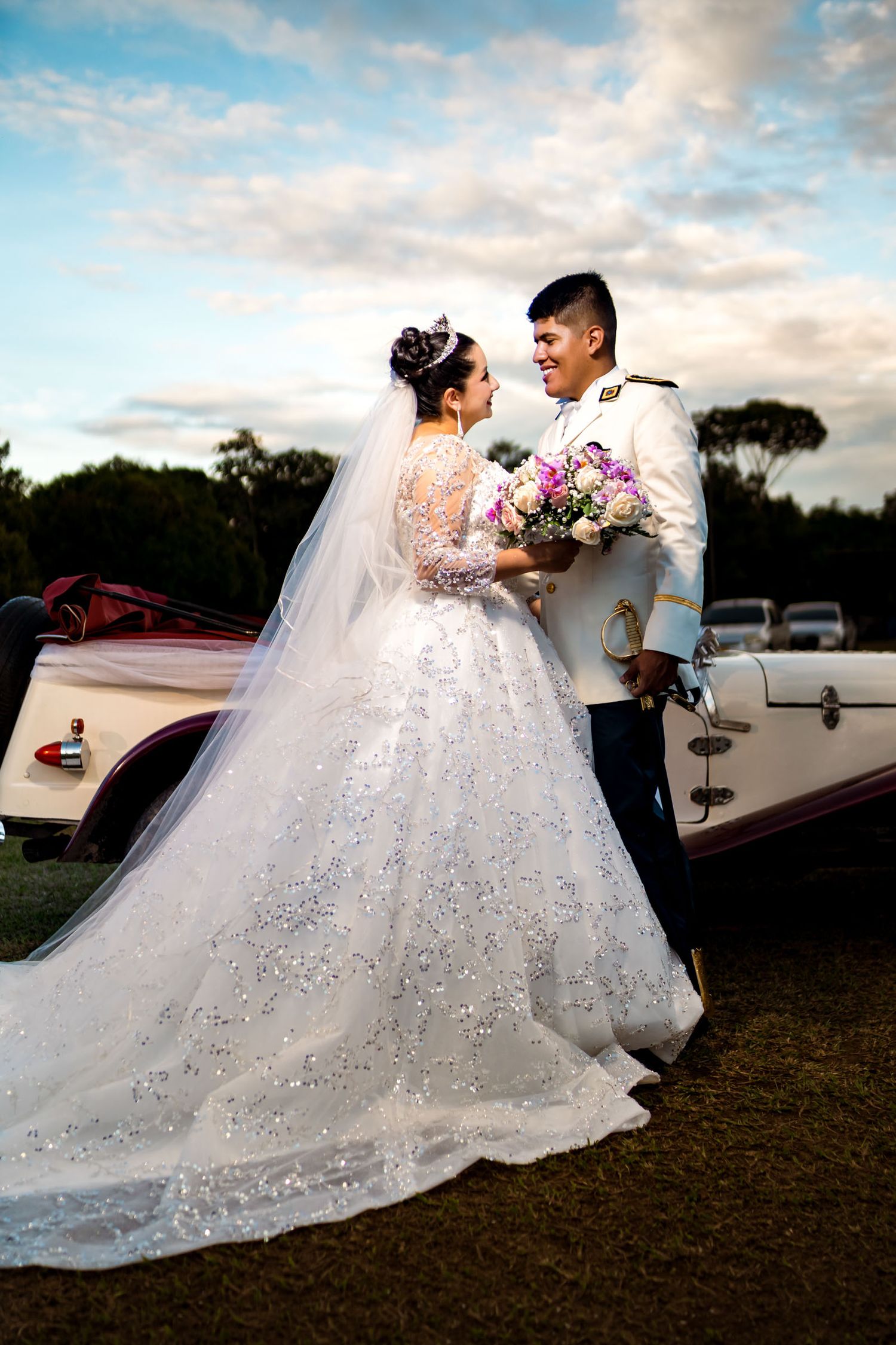 Novios posan junto a un carro clásico rojo en su sesión de fotos de boda en Villavicencio.