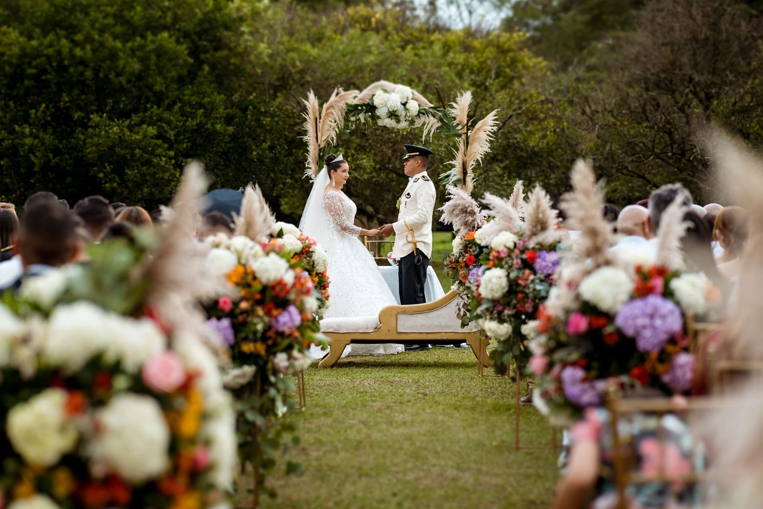 Altar de boda al aire libre decorado con arreglos florales y vista al fondo de los invitados