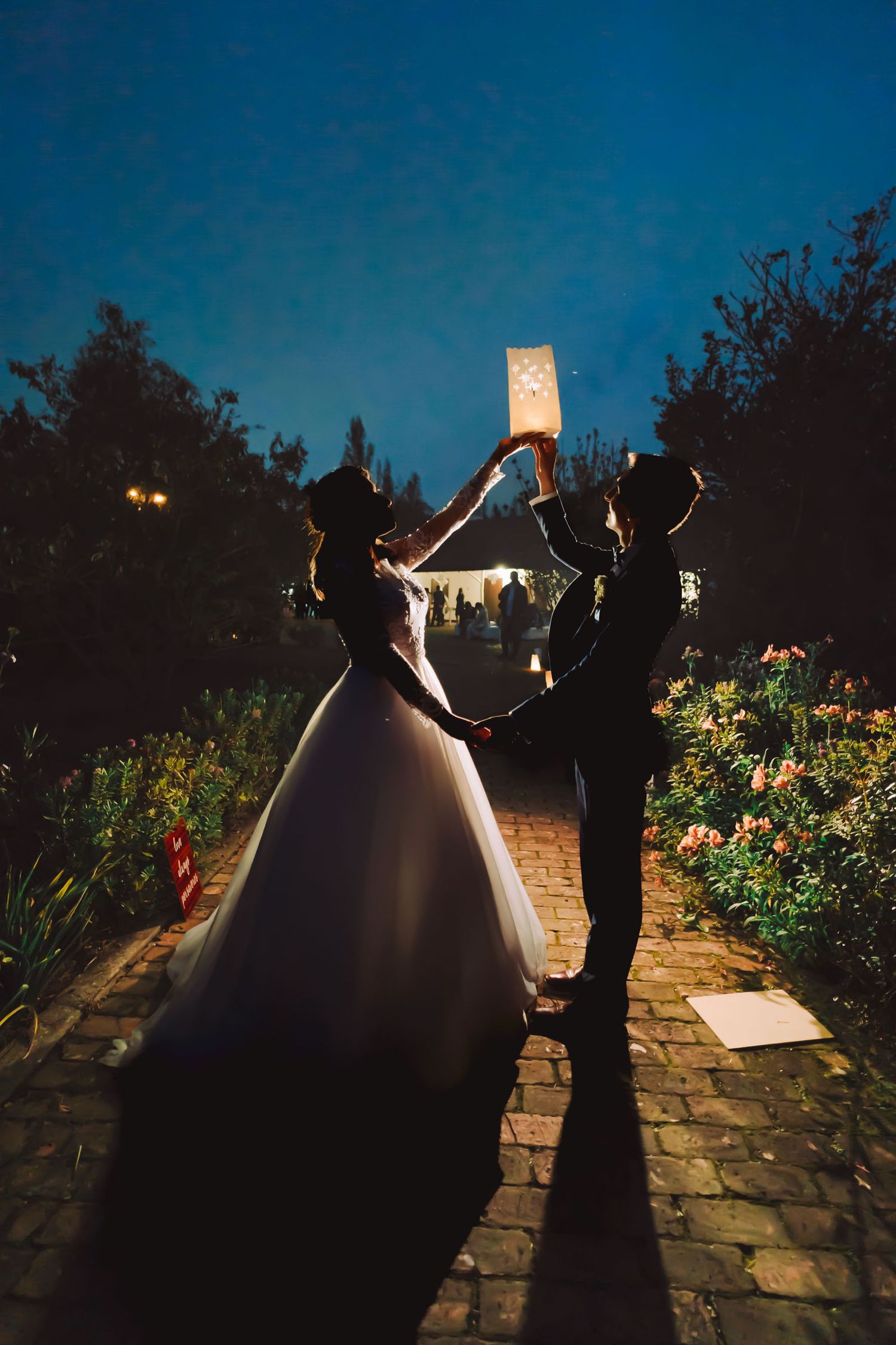 Novios caminando de noche por un sendero de jardín en Cajicá.