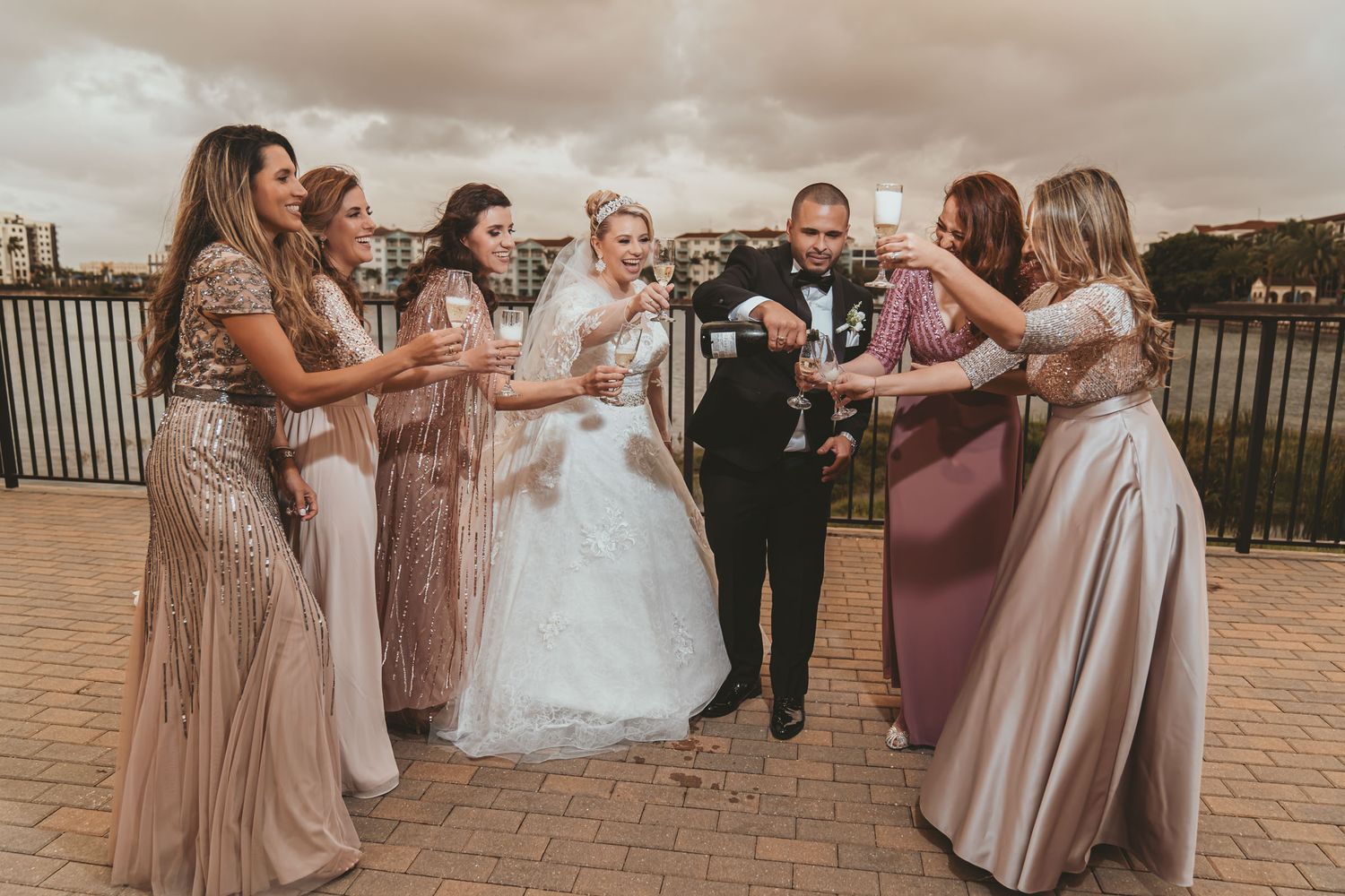 Novios se miran posando separados frente a pared moderna (madera y follaje); ella sostiene ramo. Foto boda en Miami.