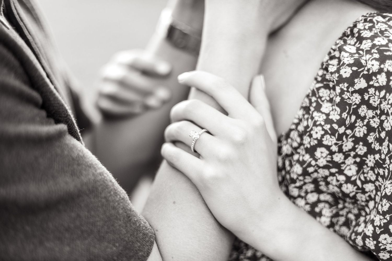 Engaged woman resting her hands on her fiancé's arms and showing off her engagement ring during engagement session in Dallas, Texas