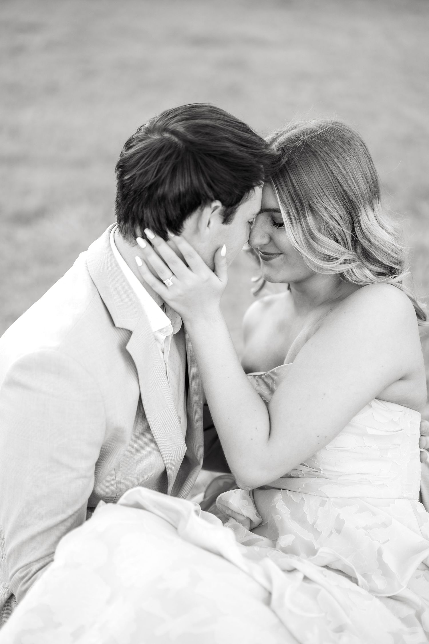 Engaged couple resting their heads together sweetly in a field at Adriatica Village in McKinney, TX during engagement session