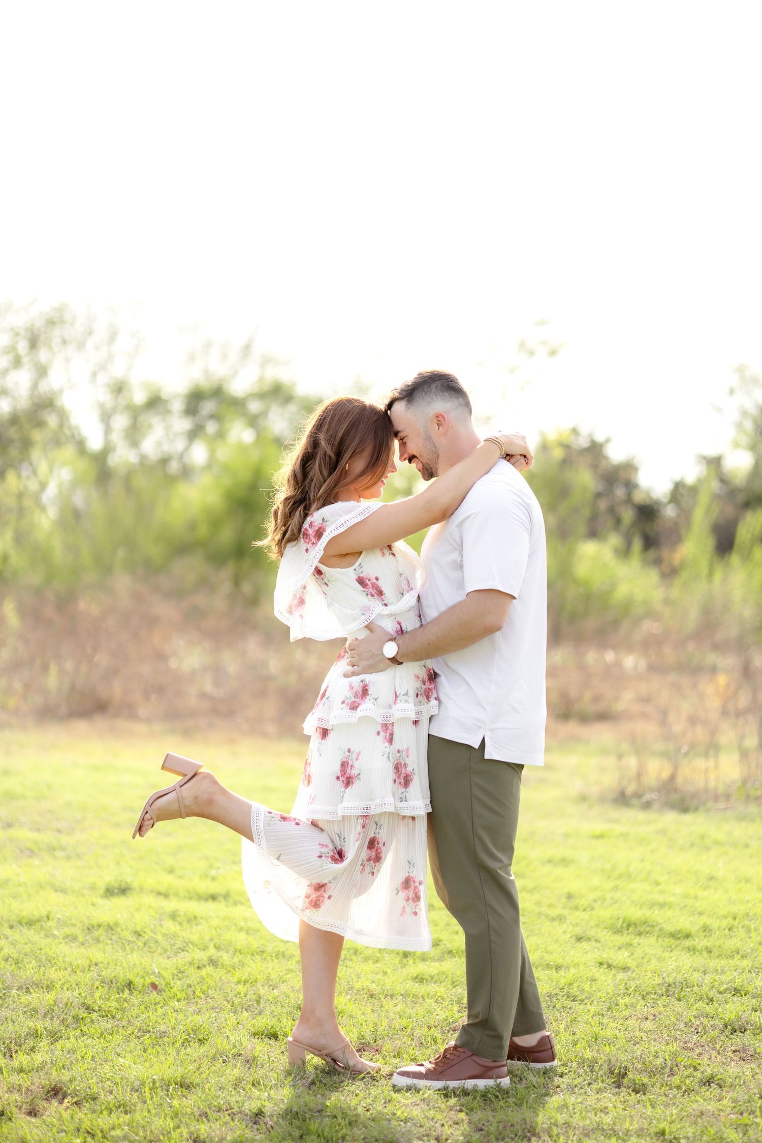 Married couple romantically resting their heads together and the wife popping up a heel in a field in Dallas, Texas
