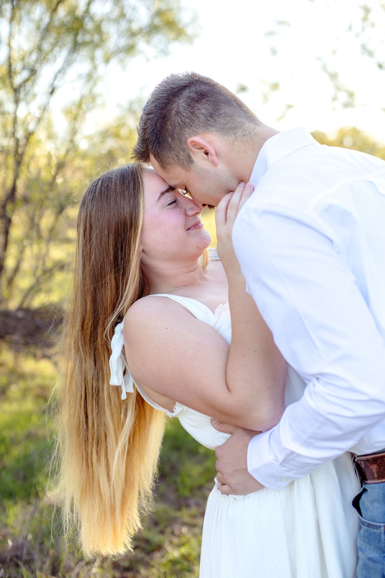 Engaged couple dipping back and resting their heads together with their eyes closed at a field in Abilene, TX