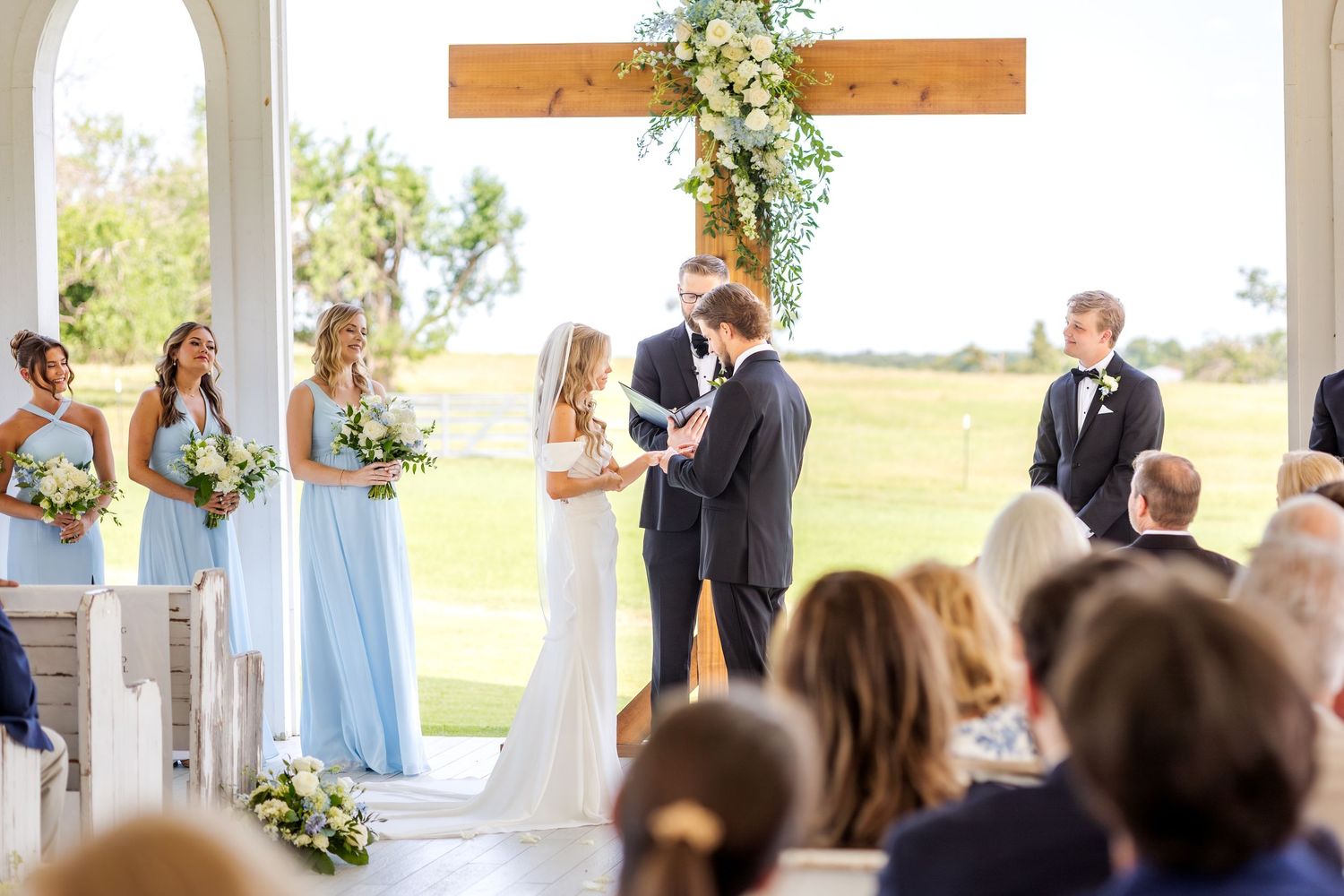 Bride placing the wedding ring on the groom's finger during Dallas wedding ceremony at Chandelier Farms