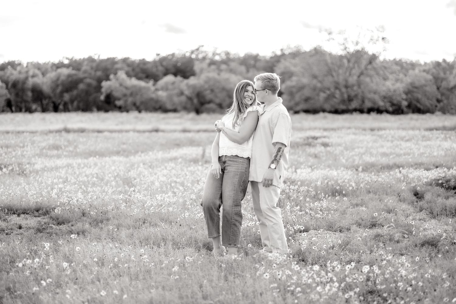 Black and white image of a wife leaning into her husband in a wildflower field in Abilene during couples photo session in Spring