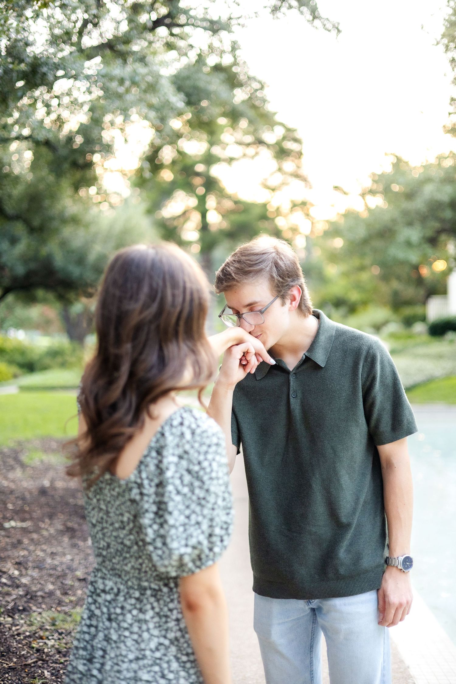 Engaged man kissing his fiancé's hand at golden hour during Dallas engagement session at Flippen Park