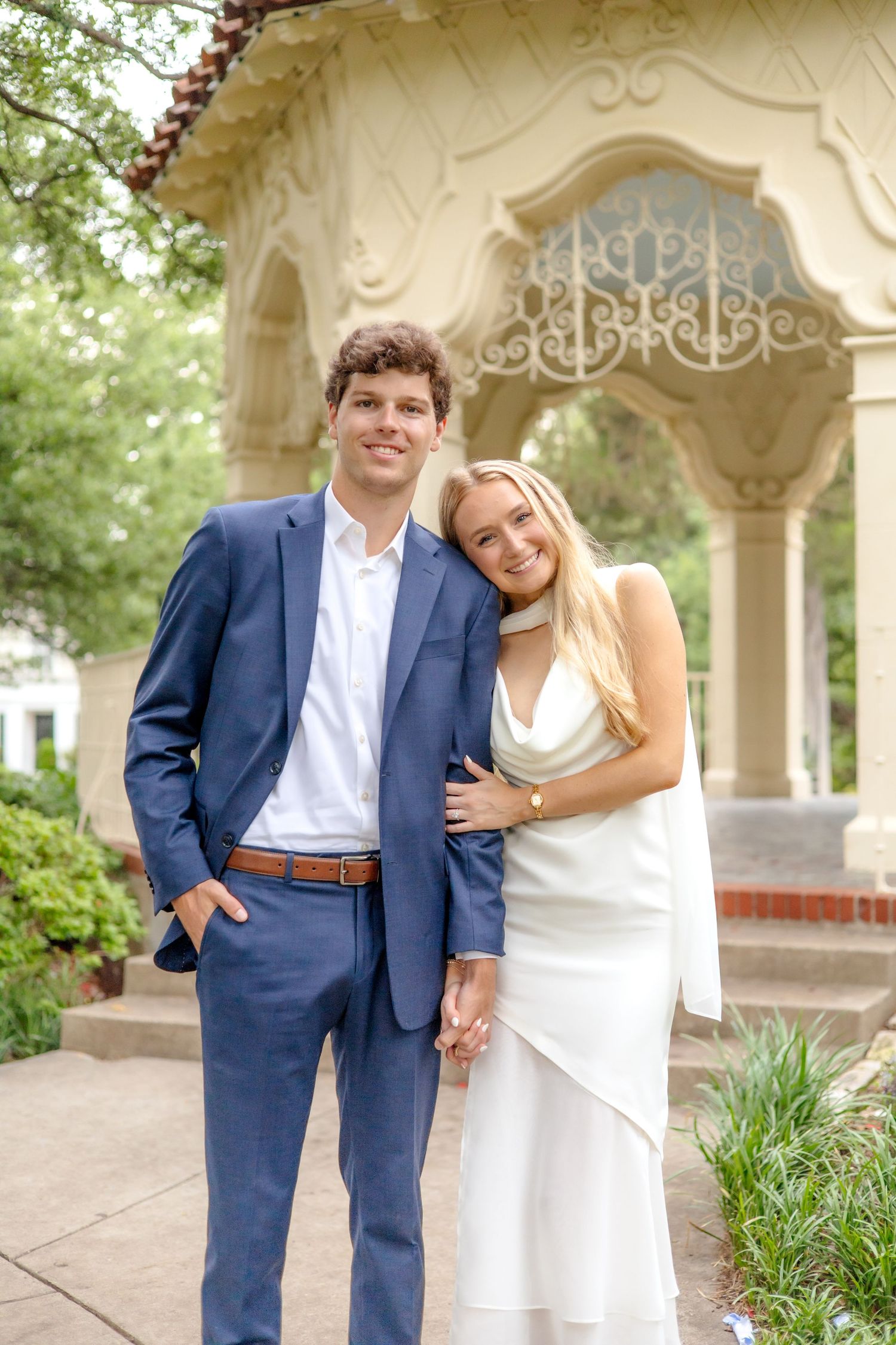 Bride-to-be leaning her head on her fiancé's shoulder next to the elegant gazebo at Flippen Park in Dallas, TX