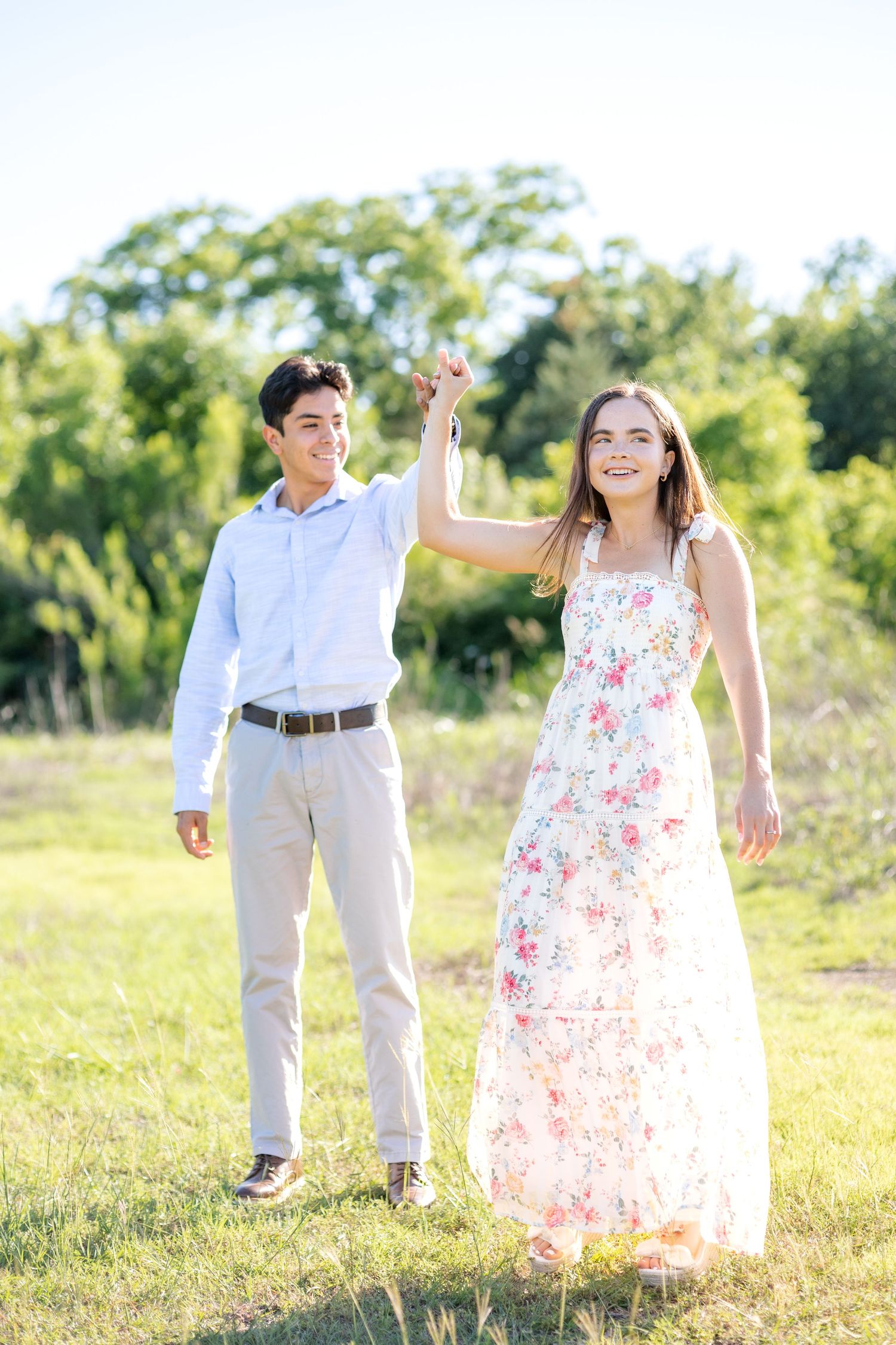 Engaged couple doing princess spins at golden hour during their dallas, texas engagement photo session at White Rock Lake