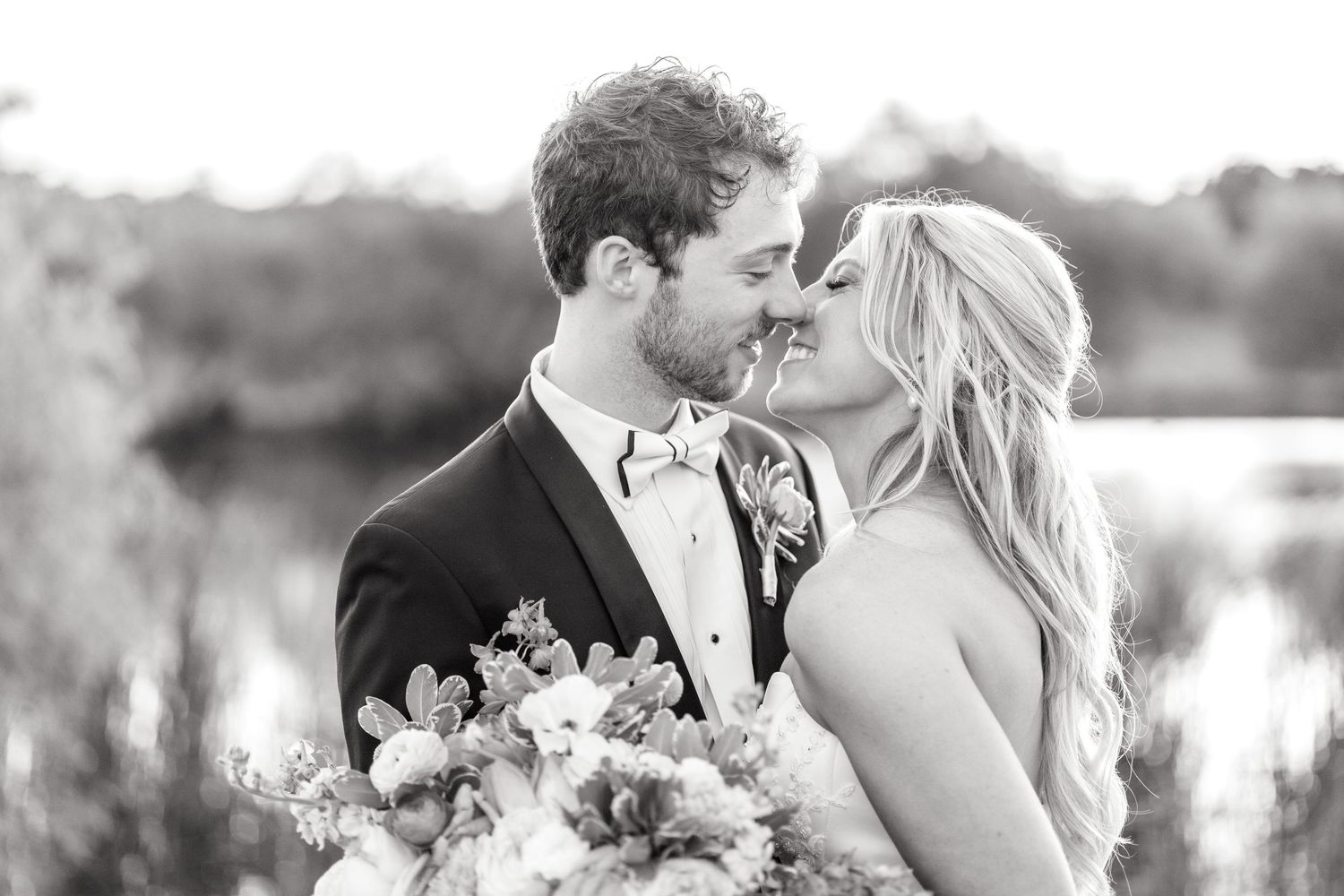 Black and white image of a bride and groom going in for a kiss during golden hour on their wedding day at The Barn at Paradise Place.