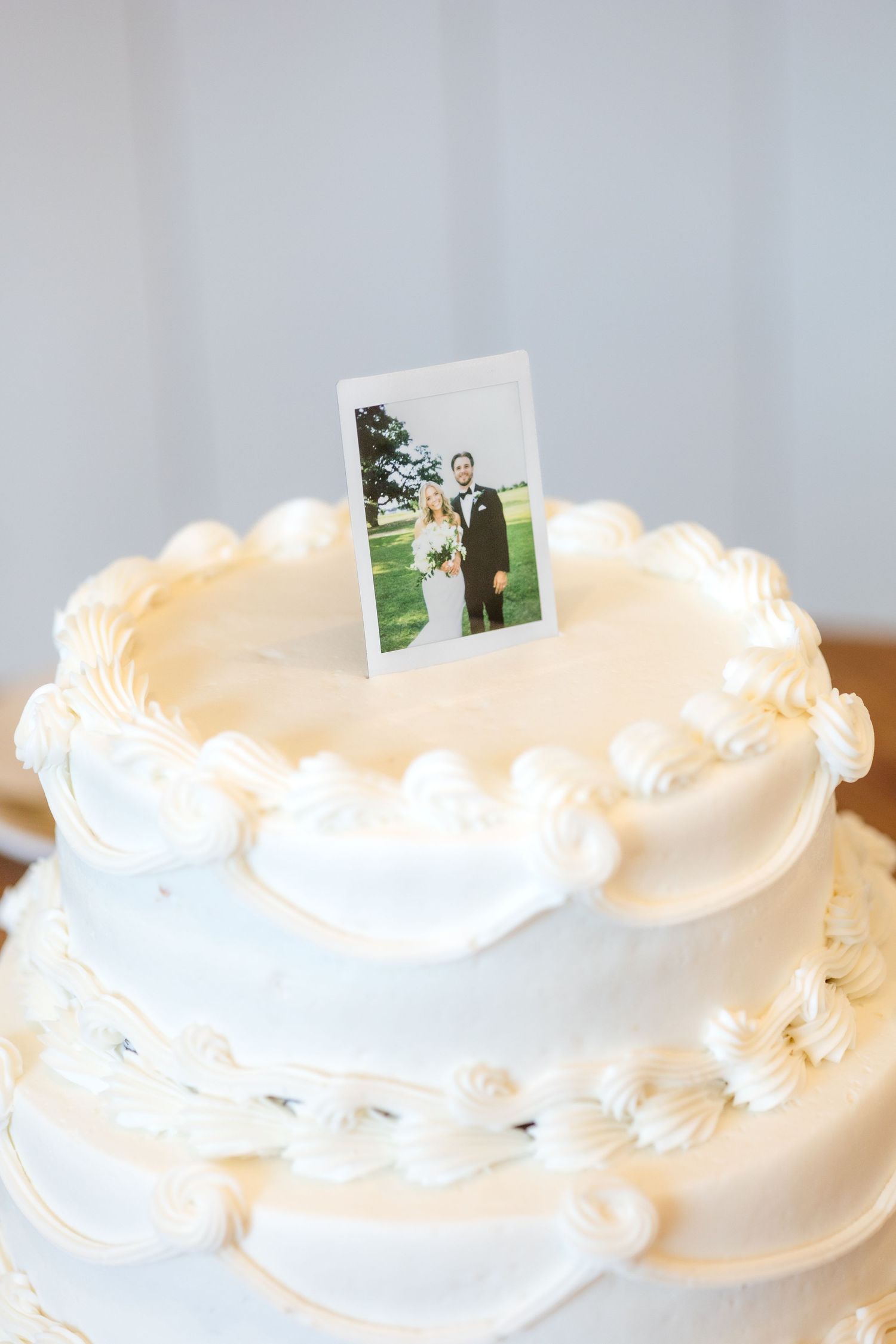 Polaroid photo of bride and groom being used as the wedding cake topper for their wedding cake