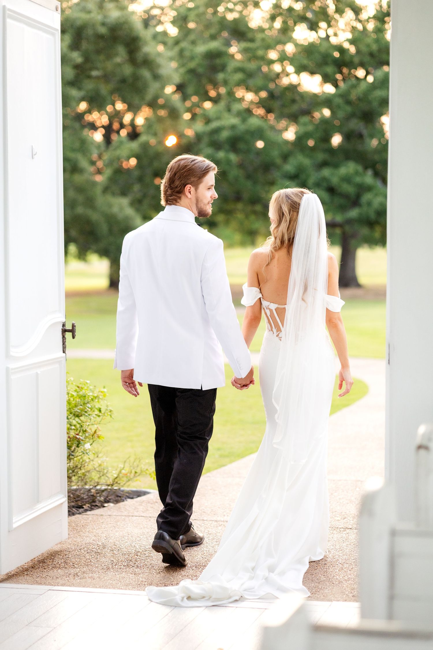 Bride and groom walking hand in hand out of a Dallas open air wedding chapel and smiling at one another