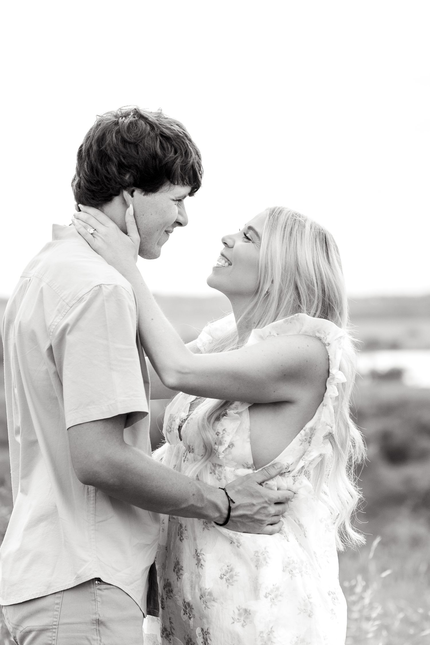 Black and white image of woman caressing her fiancé's face and romantically looking into each other's eyes