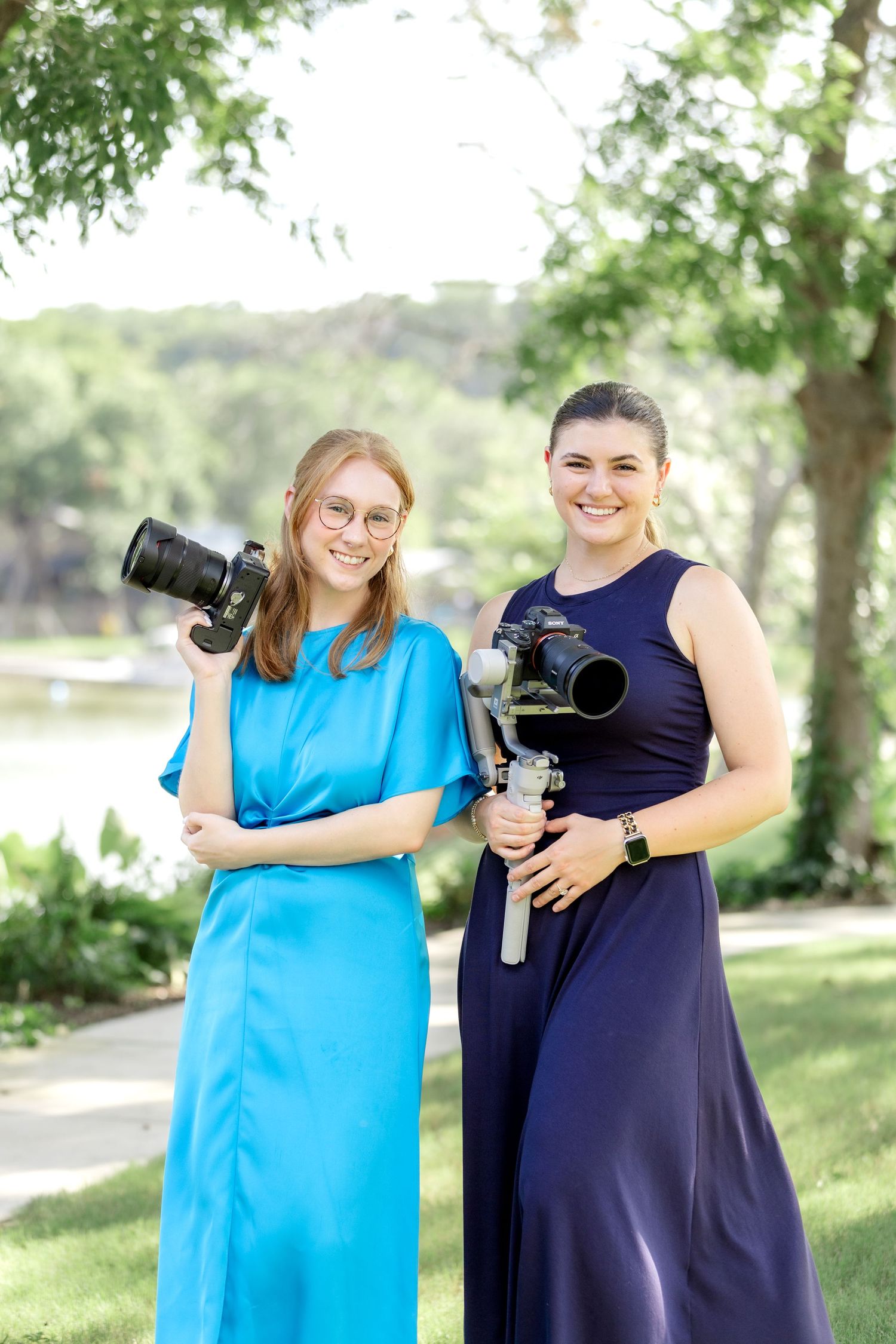 Dallas wedding photographer and videographer team standing outdoors on sunny wedding day holding their cameras