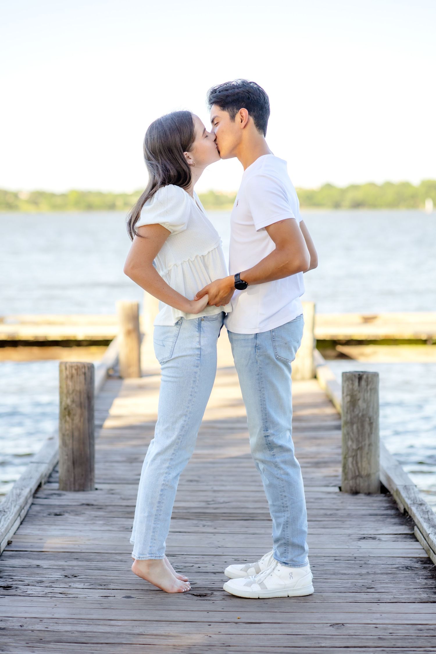Engaged couple holding hands and going in for a kiss with the bride-to-be on her tip toes during Dallas engagement photo session