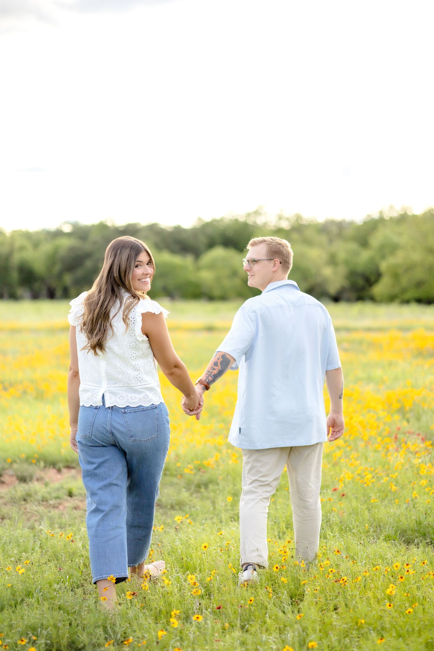 Married couple walking away hand-in-hand as she looks back and he looks at her to admire her.