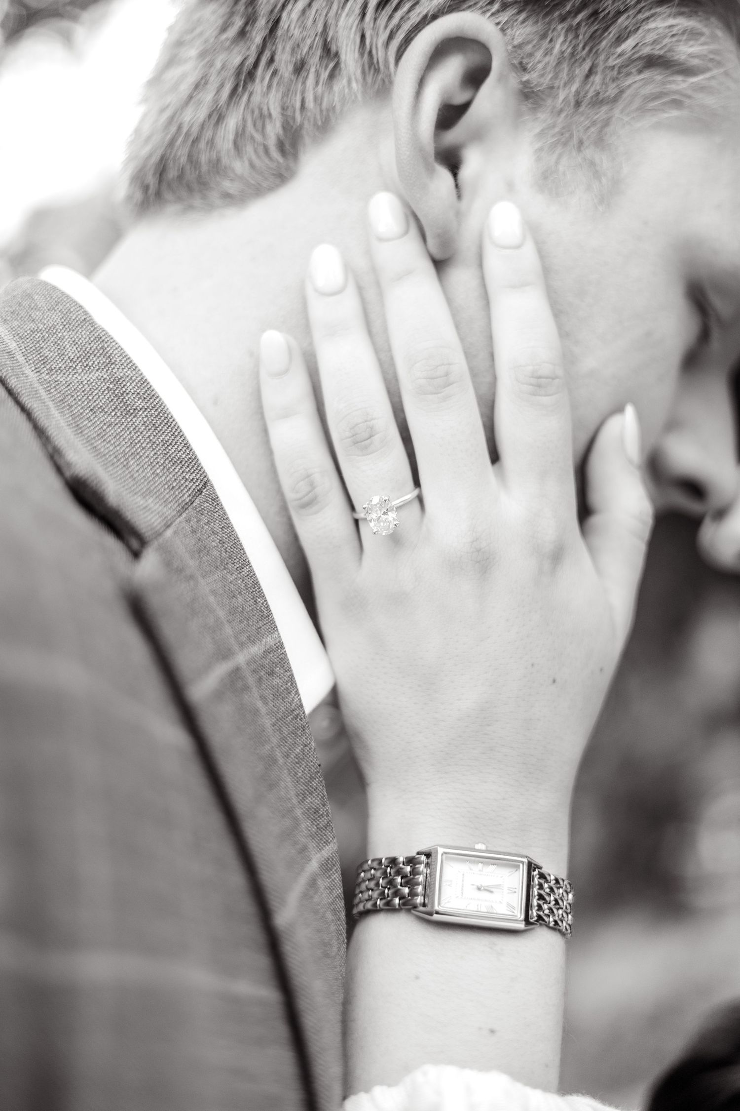 Woman's hand resting on her fiancé's cheek to showcase her engagement ring