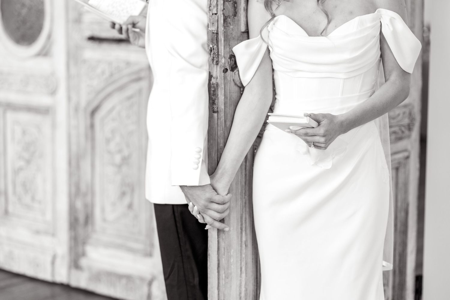 Black and white image of bride and groom holding hands during first touch and private wedding vow reading on Spring wedding day in Dallas