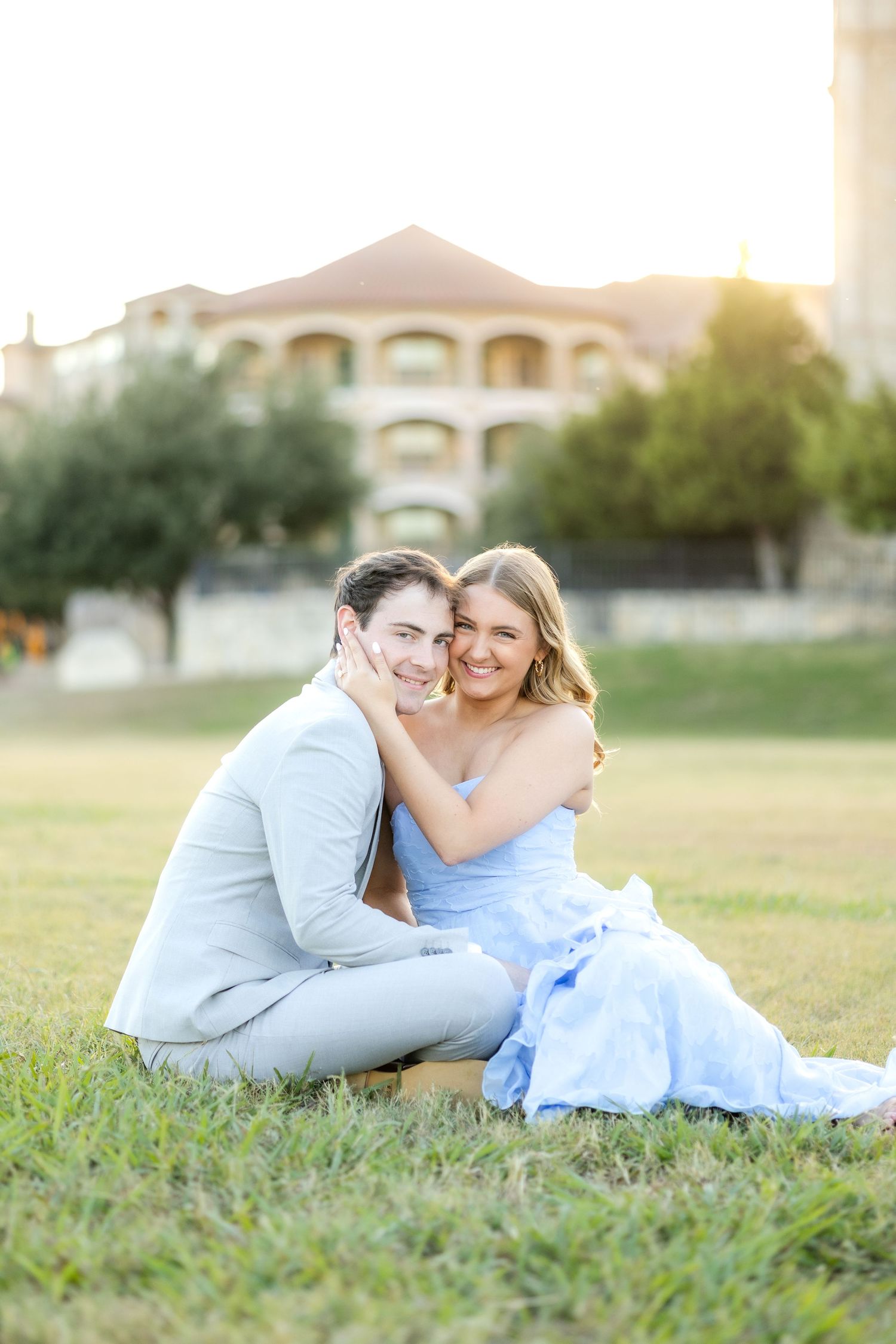 Engaged couple snuggled up to each other resting cheek to cheek in a field at Adriatica Village in McKinney, TX engagement session