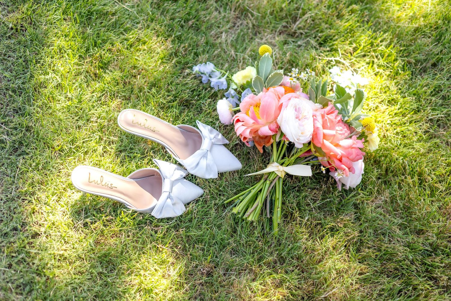 Dallas bride's wedding shoes and wedding bouquet laying in the grass at Dallas wedding venue