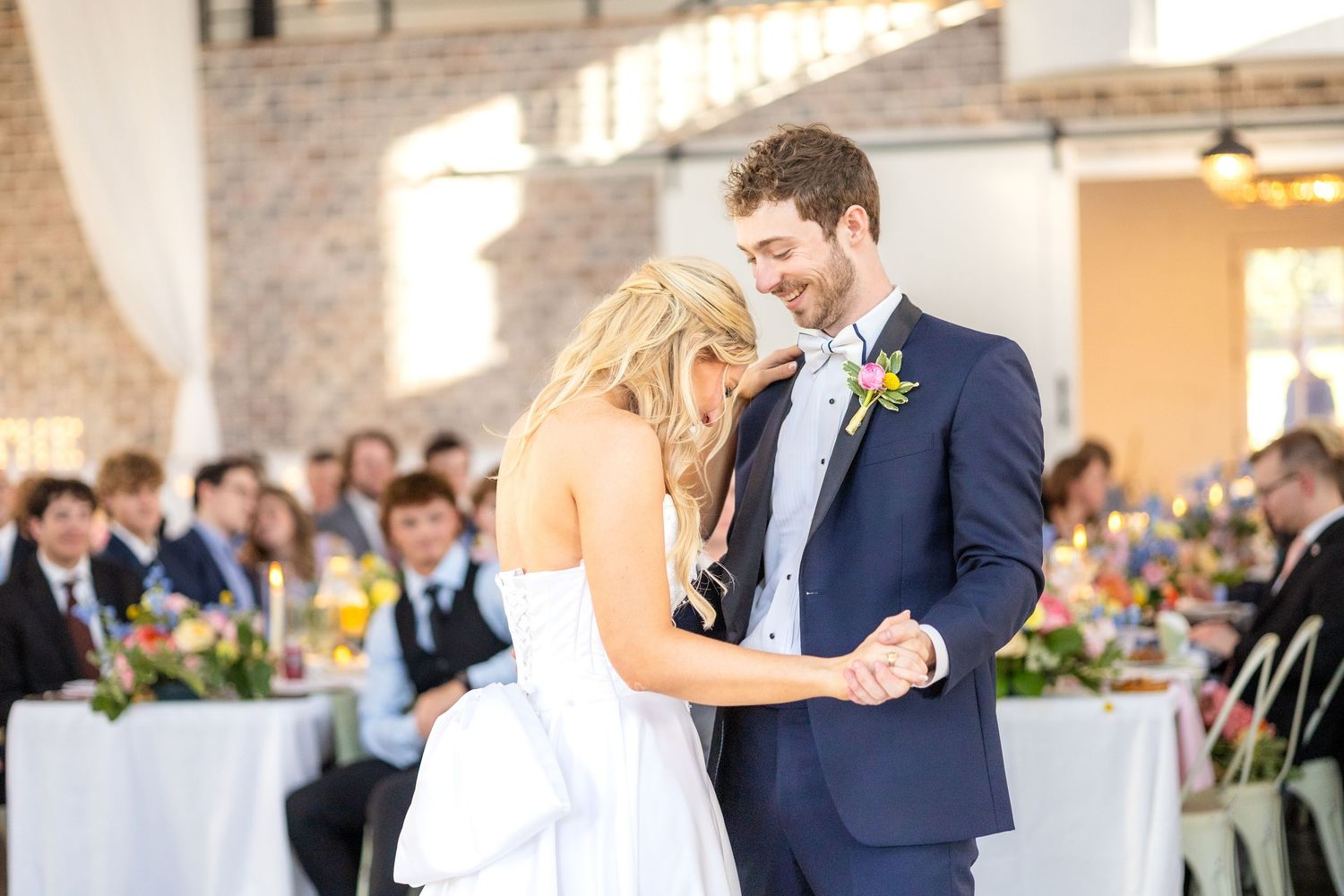 Bride and groom laughing and smiling with one another during their first dance at their wedding reception in Dallas, Texas