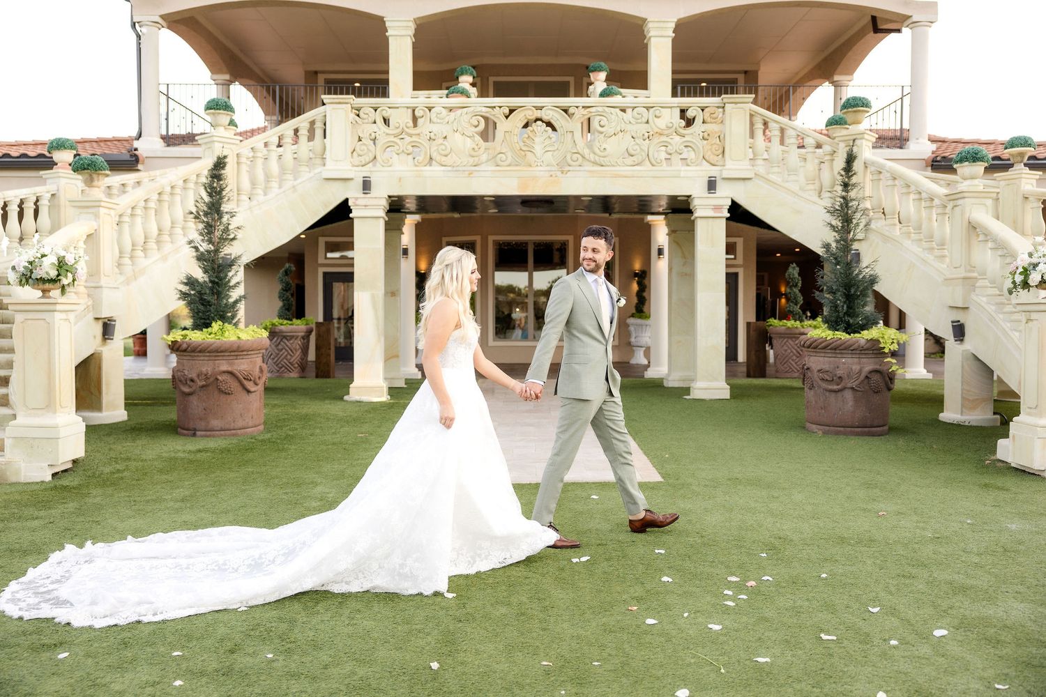 Bride and groom walking past grand staircase Dallas wedding venue