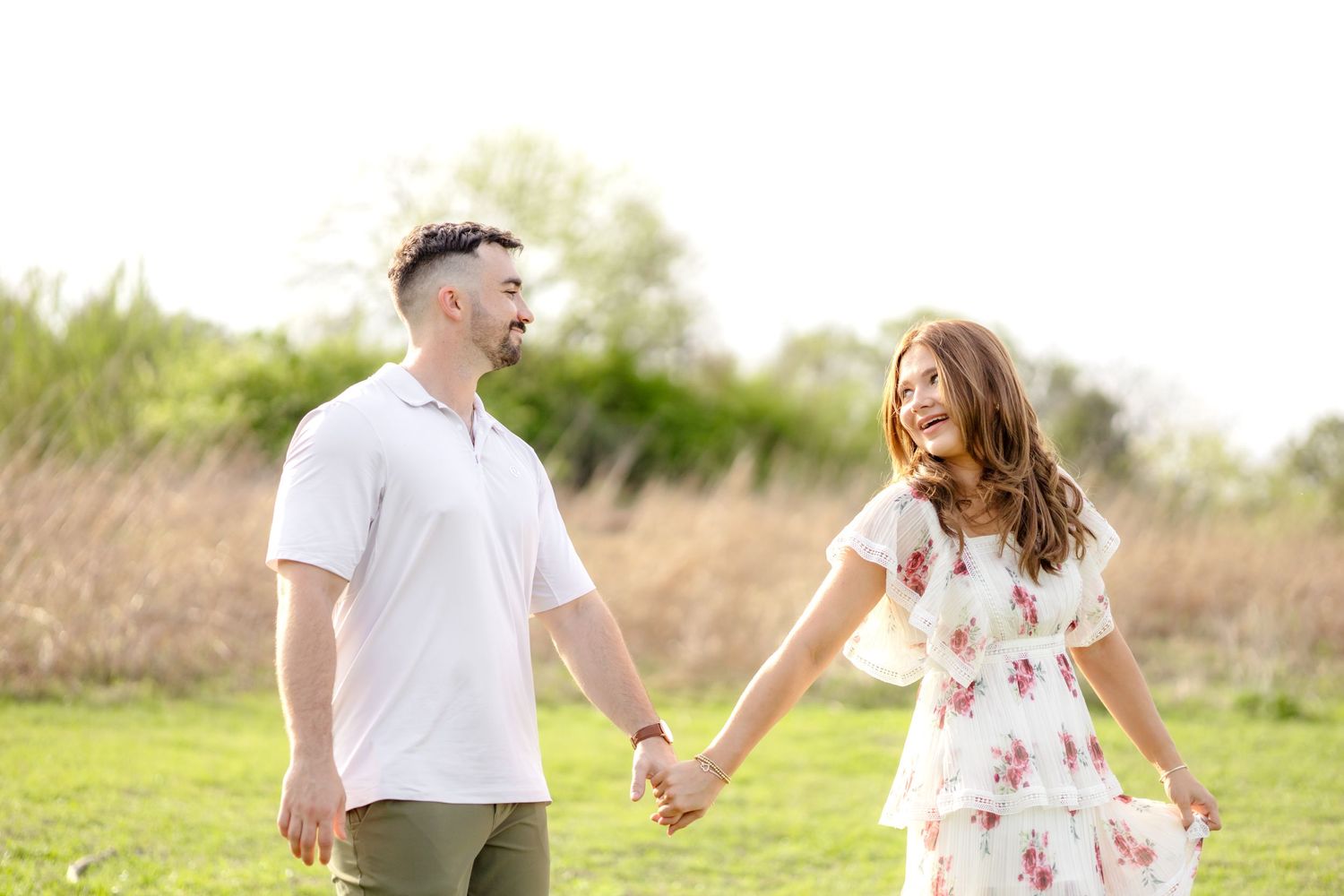 couple walking hand-in-hand in a field at White Rock Lake in Dallas, TX during a couples photo session