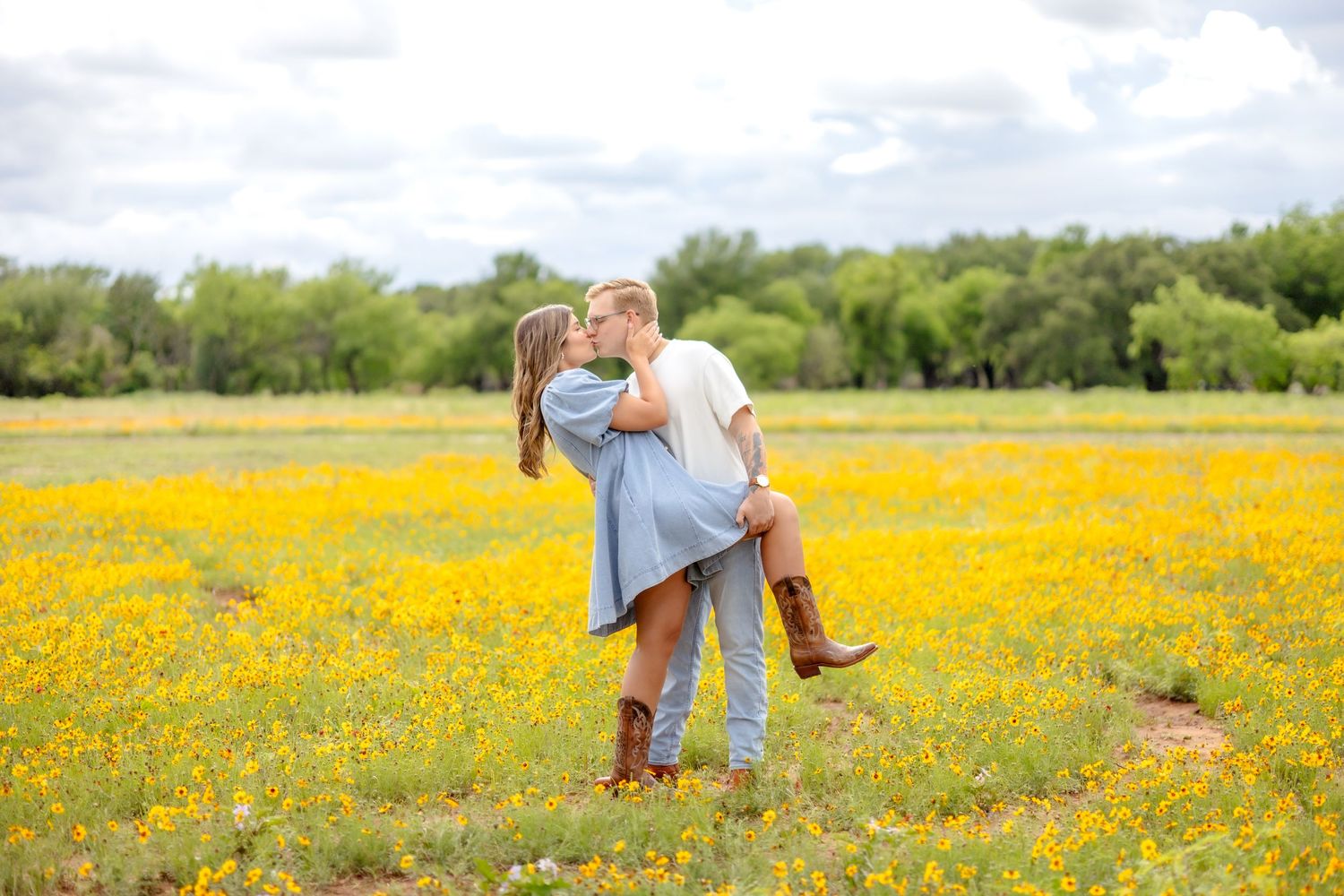Married couple sharing a dip kiss in a large wildflower field in Abilene, TX during couple's photo session