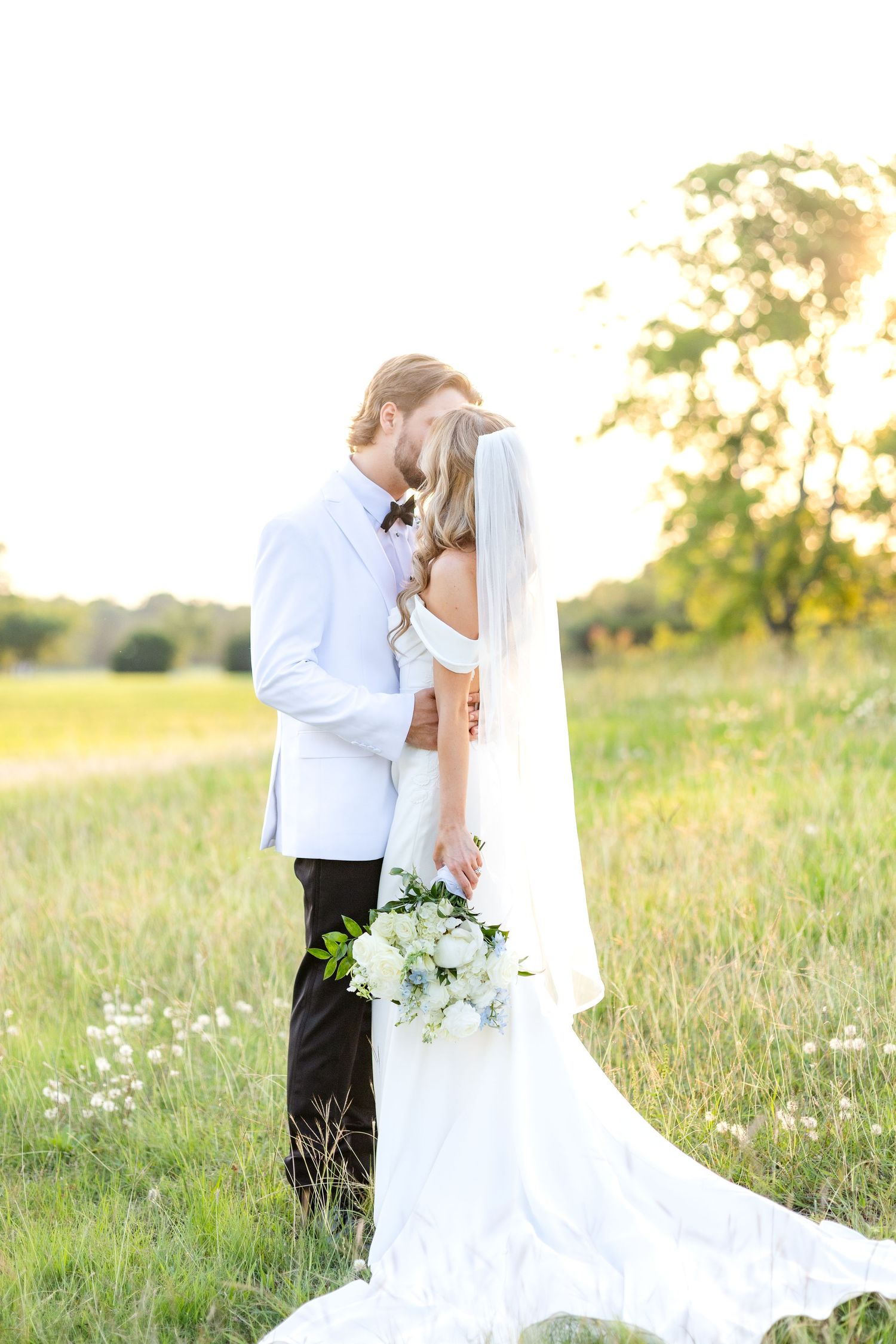 Bride and groom sharing a kiss in a field at golden hour