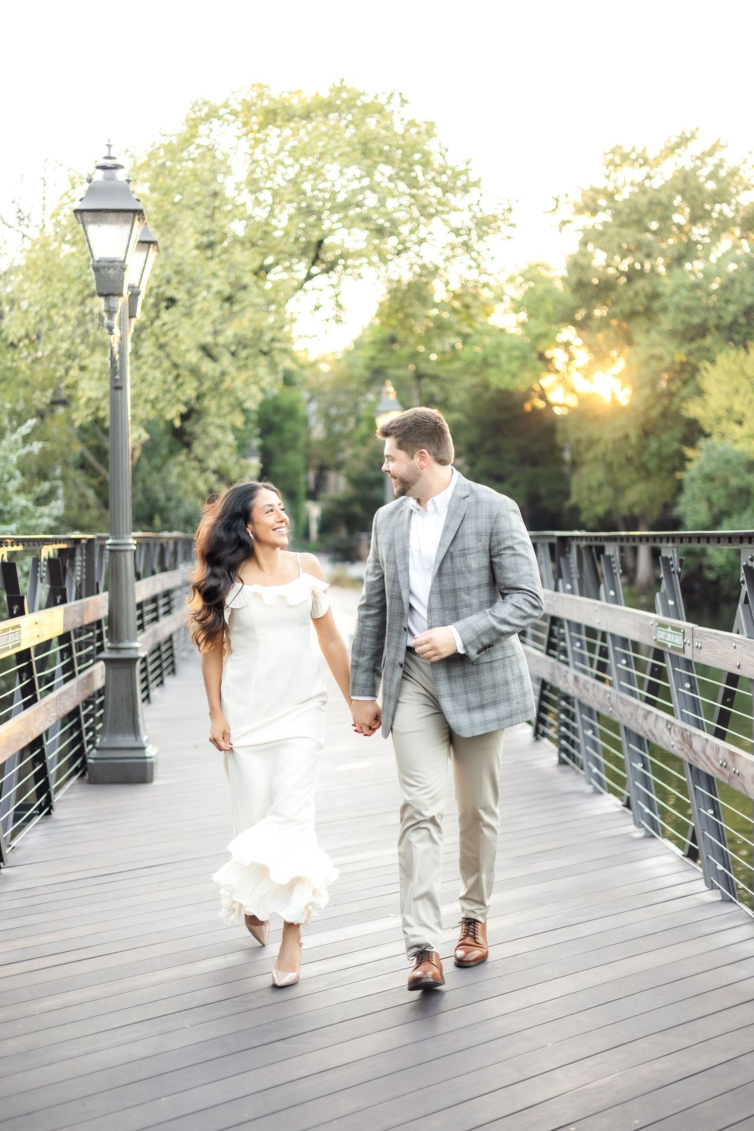 Engaged couple running on bridge at Lakeside Park in Dallas while smiling and laughing during engagement session