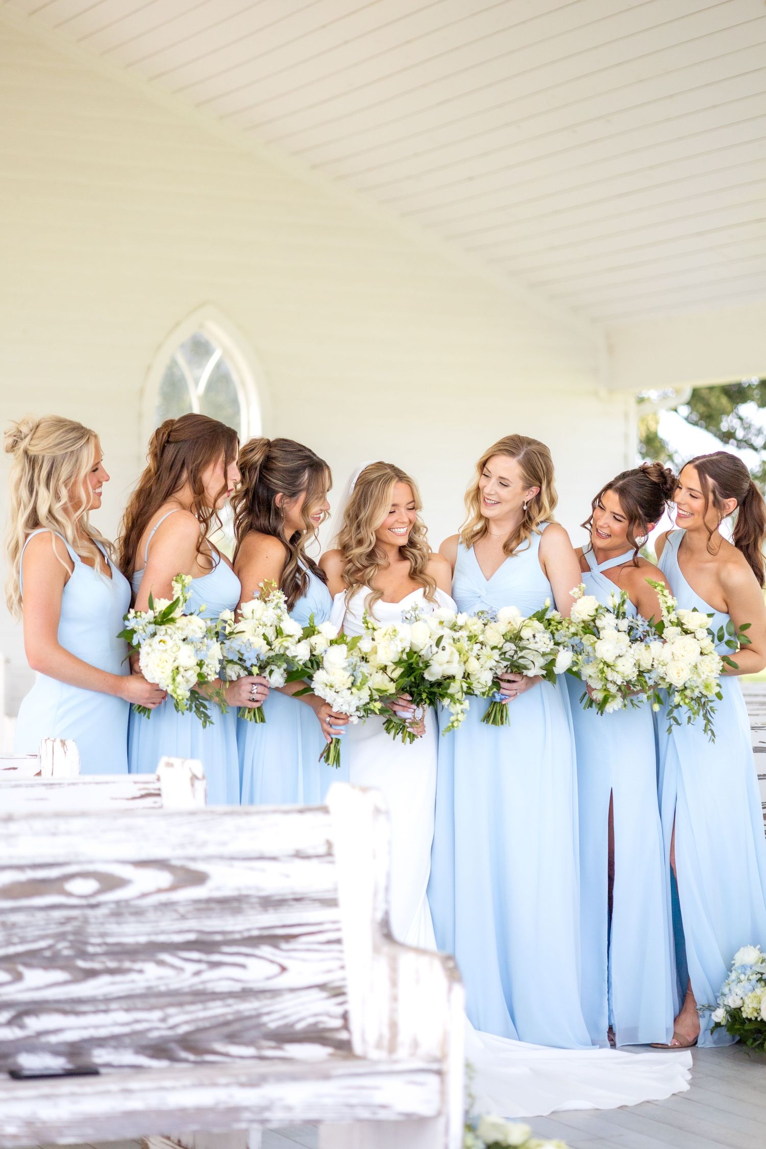 Bride and bridesmaids laughing together in wedding chapel at Chandelier Farms with Spring wedding florals
