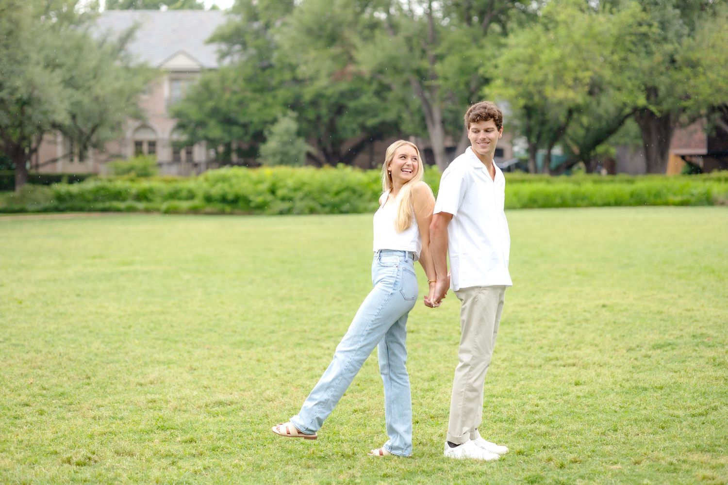 Engaged couple standing back to back and playing around at Flippen Park in Dallas, Texas