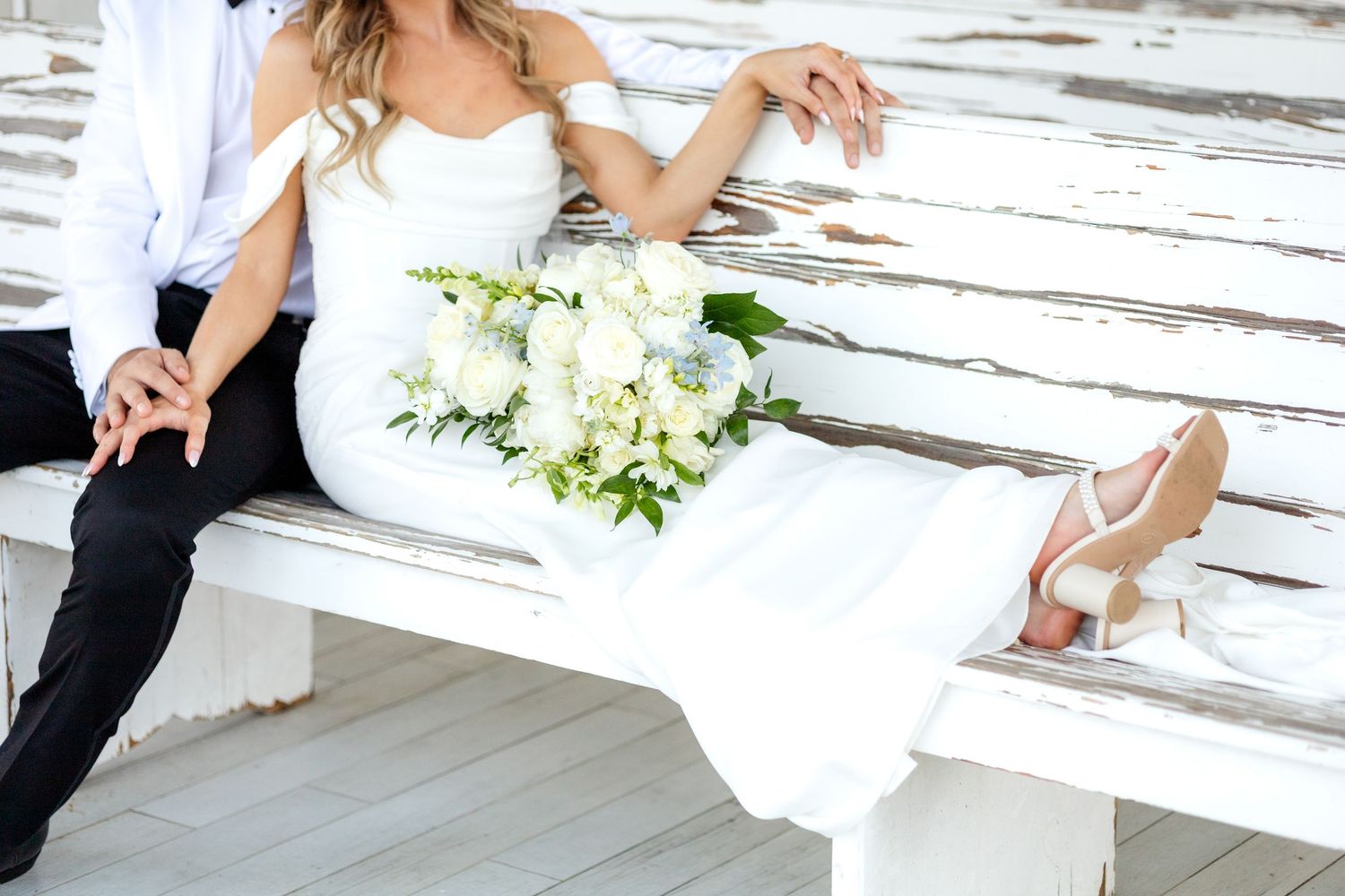 Bride lounging on a wedding chapel pew in Dallas next to her new husband with her Spring bridal bouquet resting in her lap