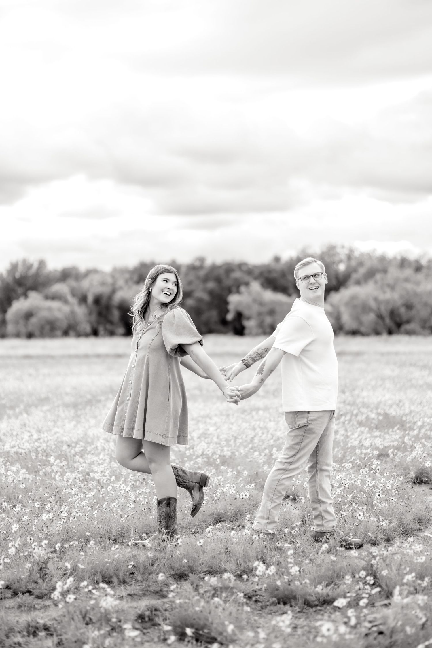 Husband and wife back to back and holding hands while playing around in a wildflower field