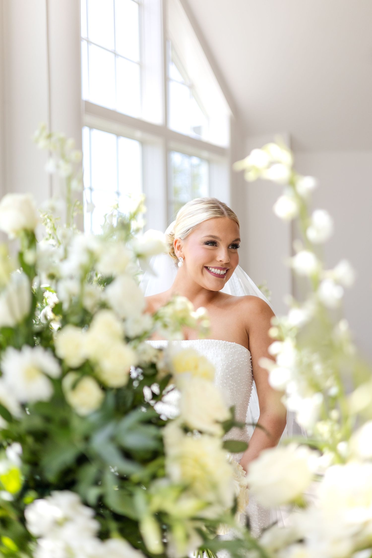 Bridal portrait peeking through summer wedding flowers at Dallas wedding