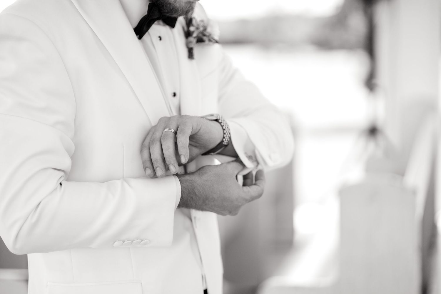 Black and white image of groom adjusting his wedding cufflinks inside a Dallas wedding chapel