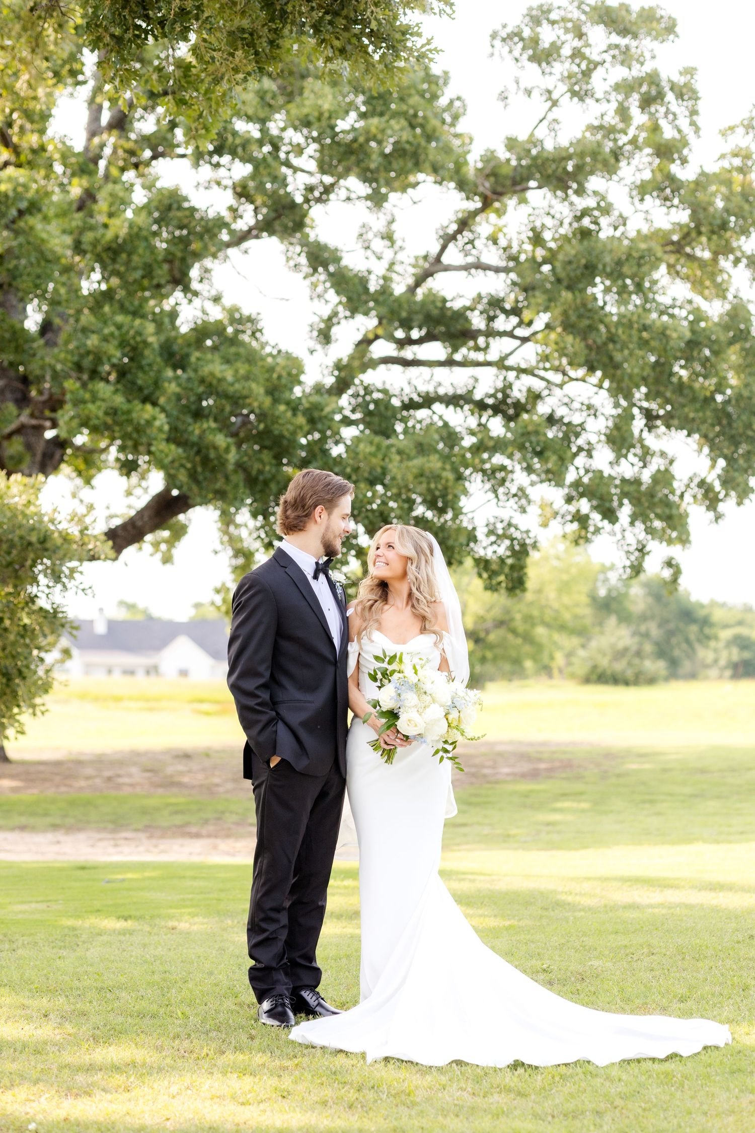 Bride and groom standing side by side and smiling at one another in a field at Chandelier Farms