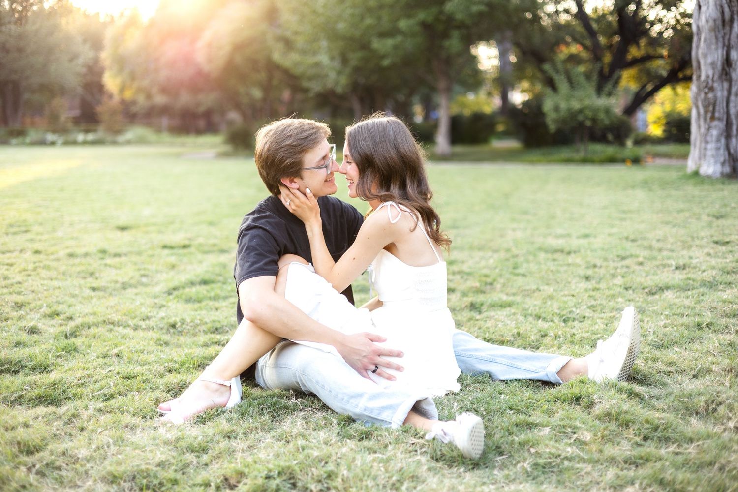 Engaged couple sitting cuddled up with each other and resting their noses together at Flippen Park in Dallas, TX during engagement session